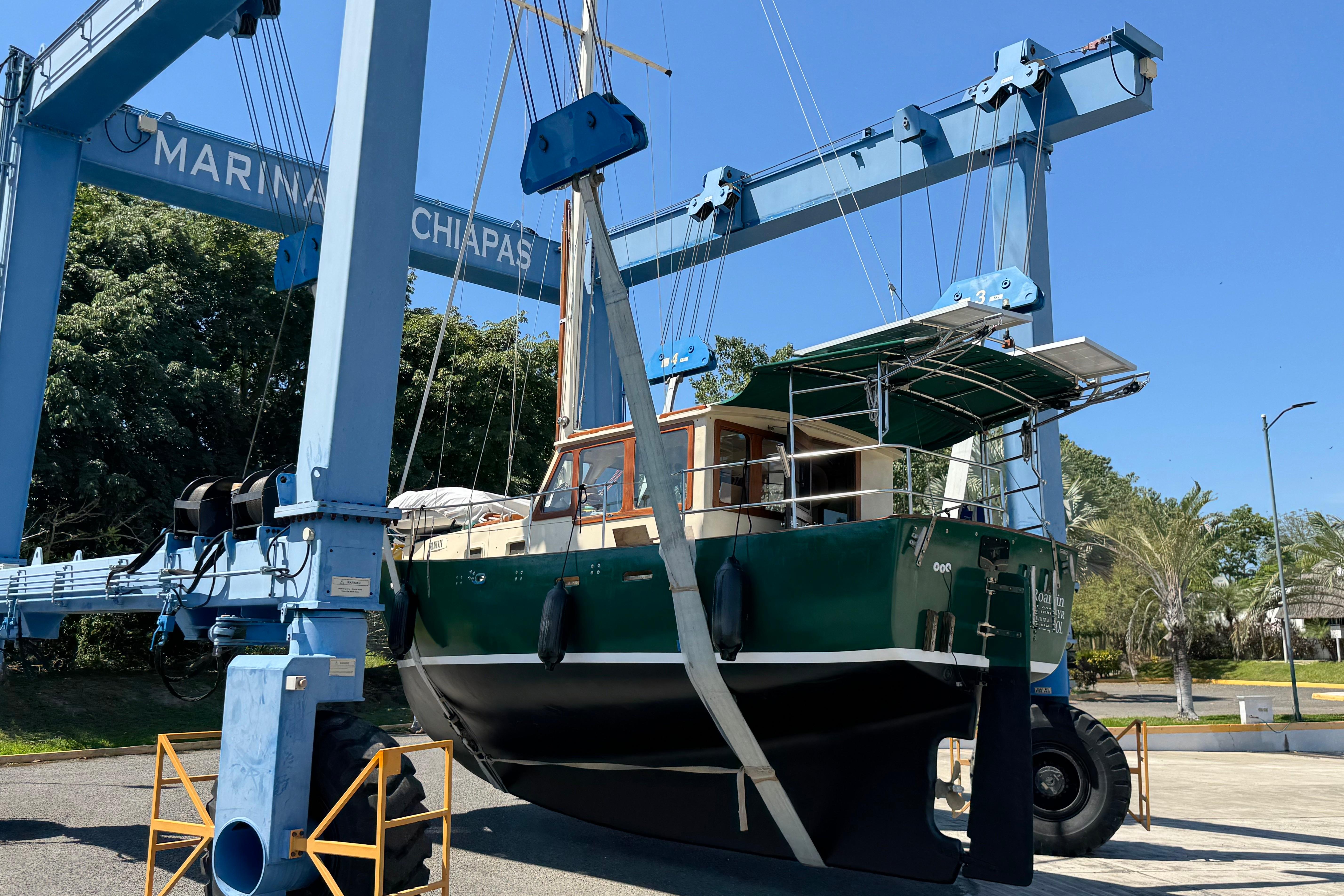 1984 Custom Kodiak 30 boat lifted at Marina Chiapas, surrounded by trees and clear sky.