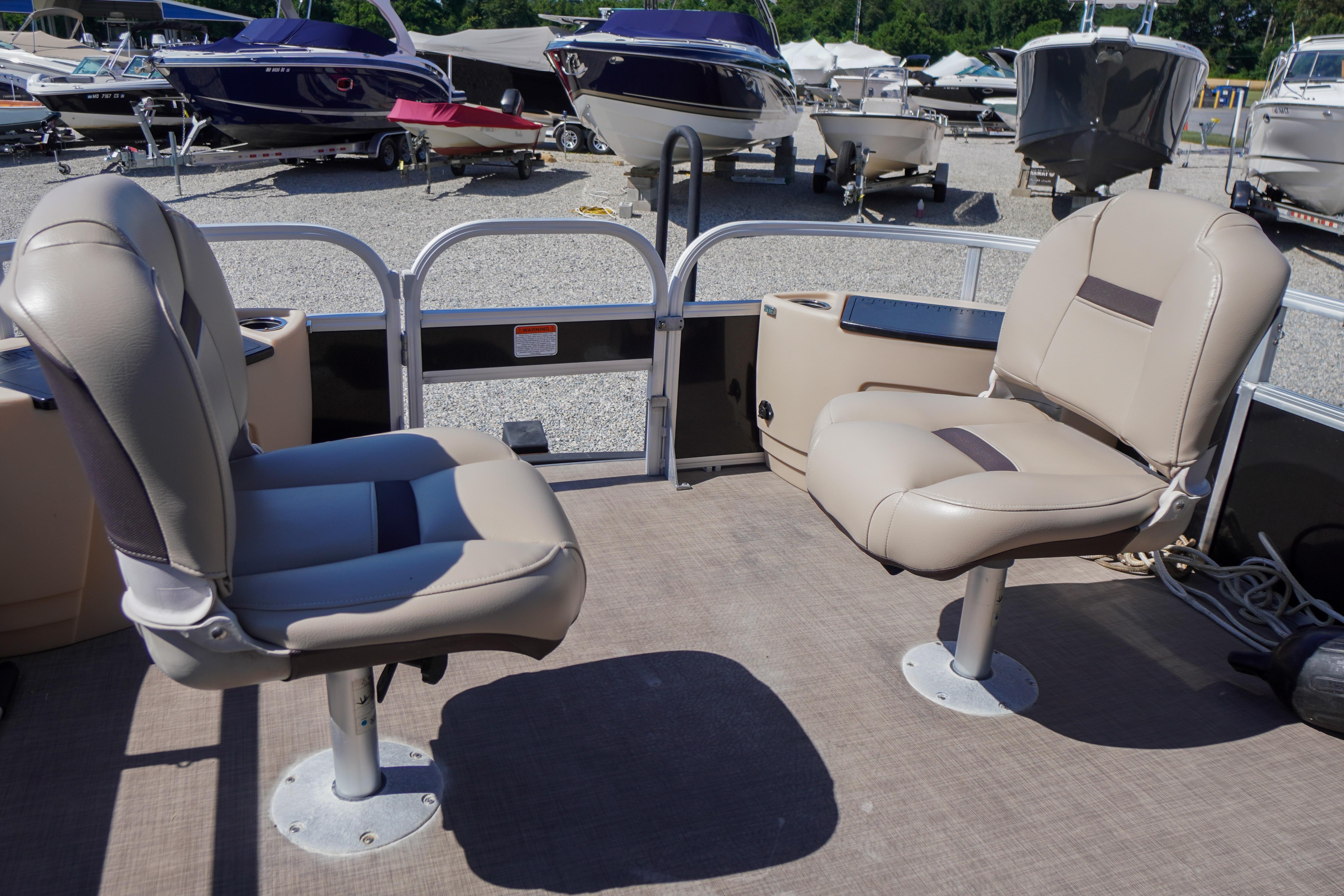 2019 SUNTRACKER Fishin' Barge 22 DLX with beige seating in a boatyard.