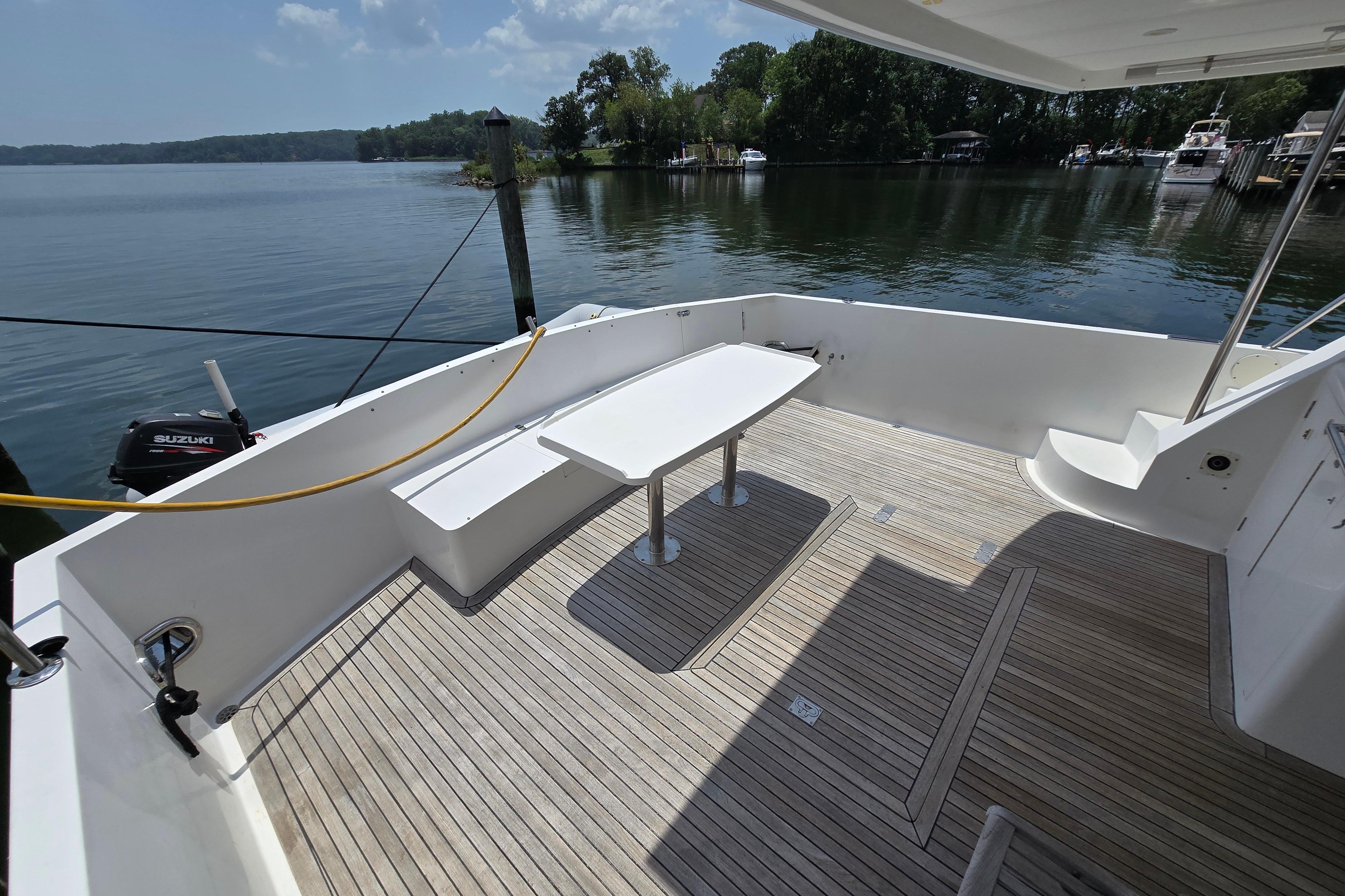 Spacious deck of 2004 Grand Harbour 58 yacht with wooden flooring and seating area.