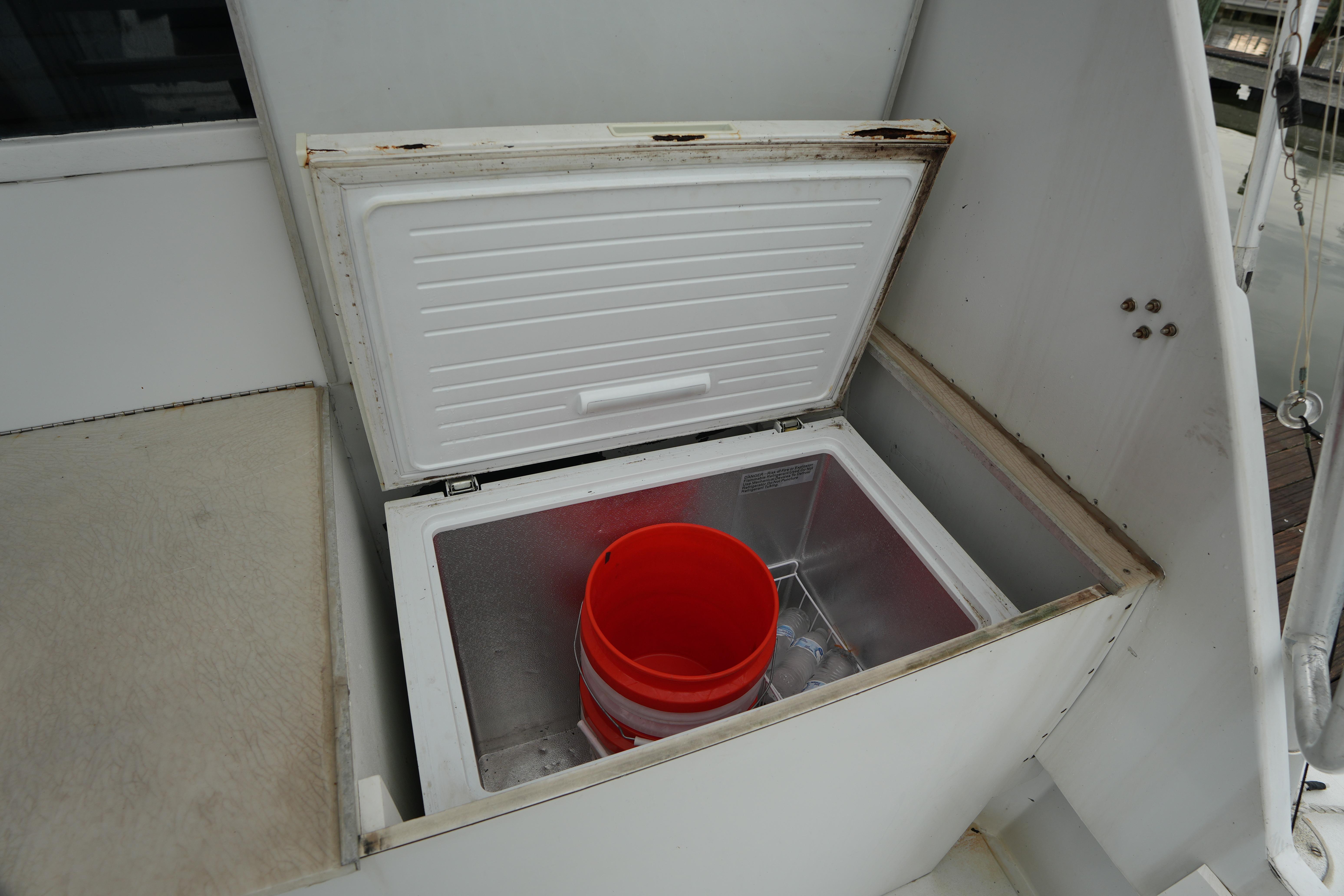 Open storage compartment on 1980 Hatteras 50 Convertible boat with red bucket inside.
