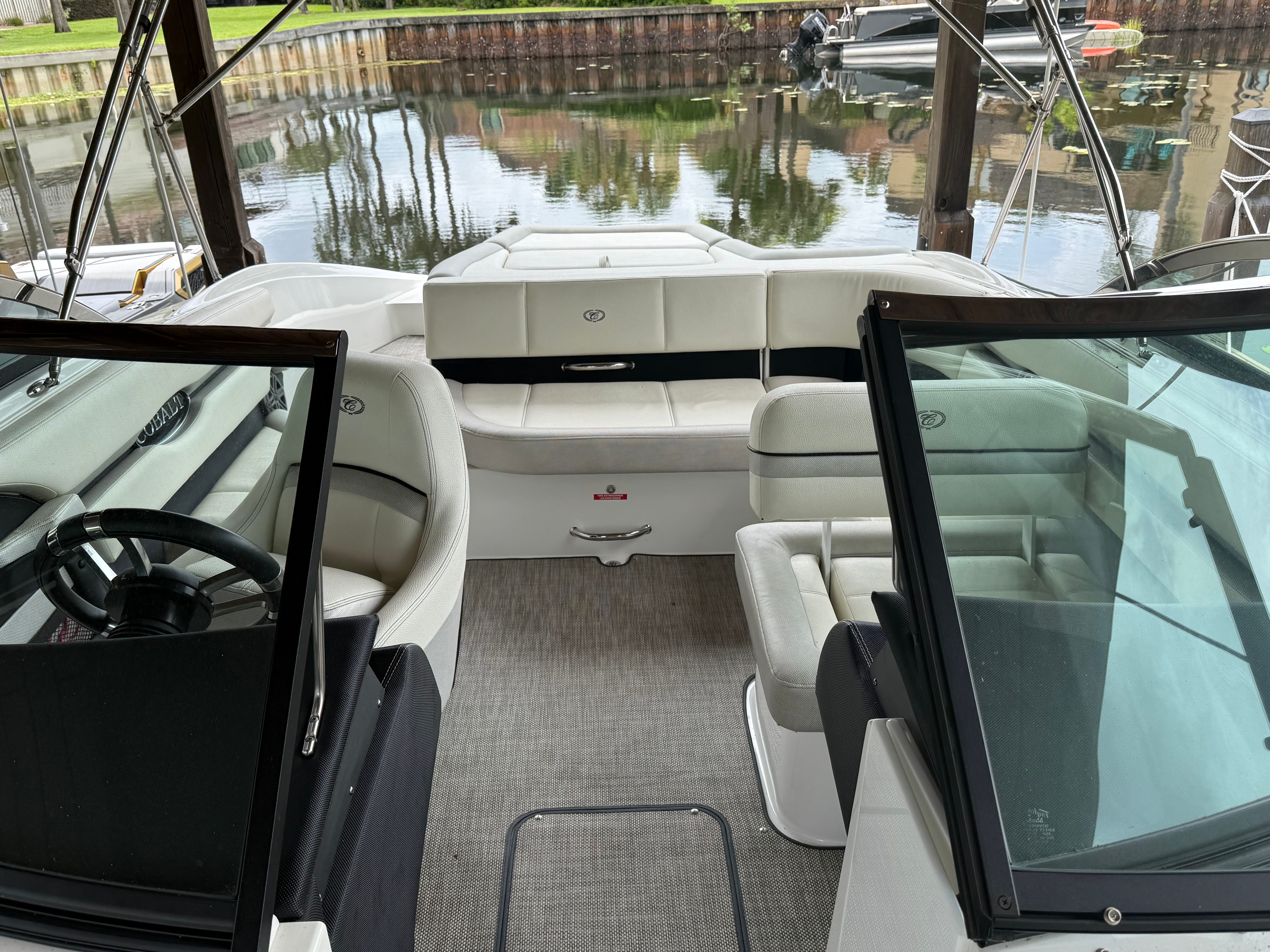 The boat features white leather seats and is docked by a calm canal.