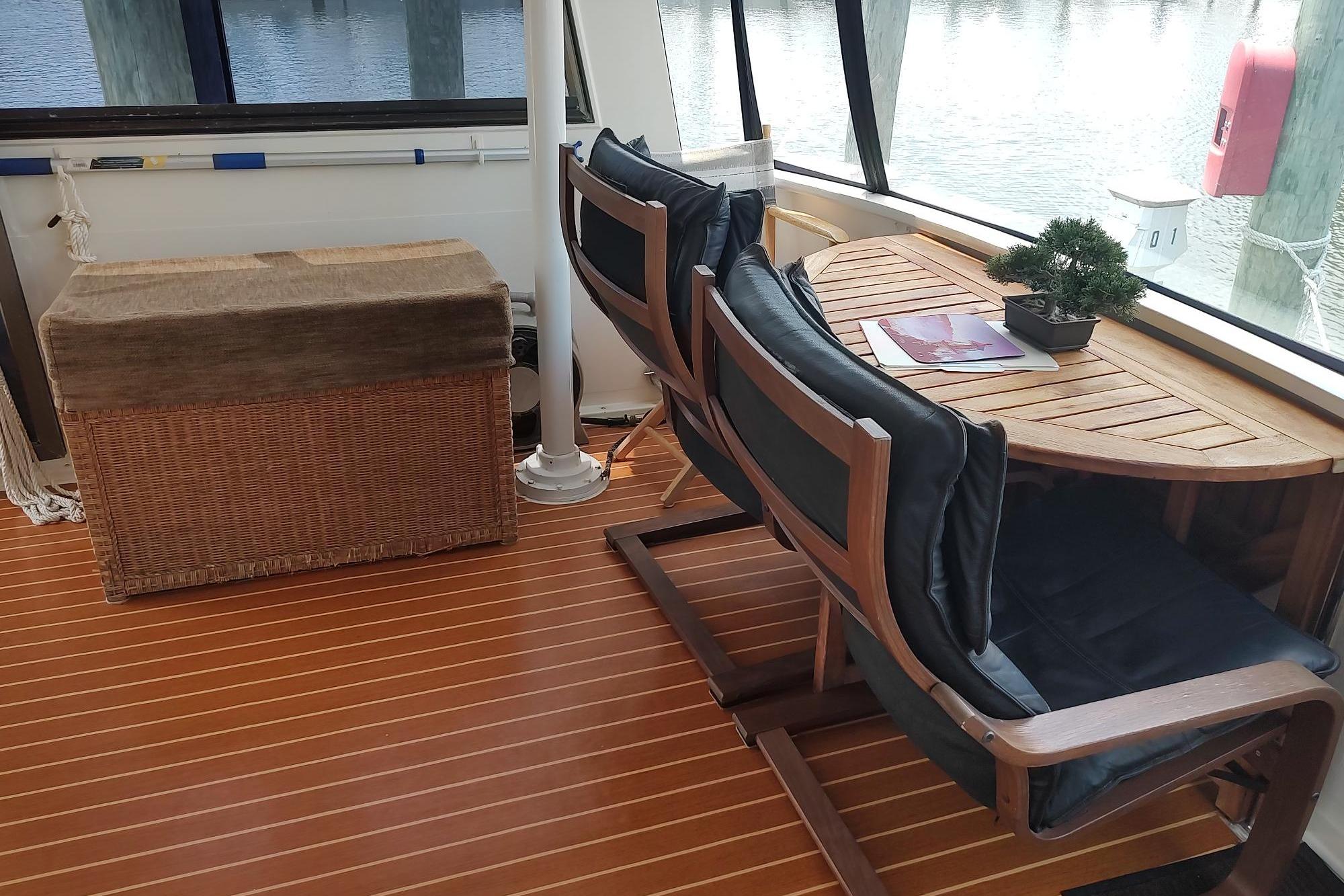 1989 Hyatt Double Cabin Motoryacht interior with wooden table, chairs, and wicker storage.