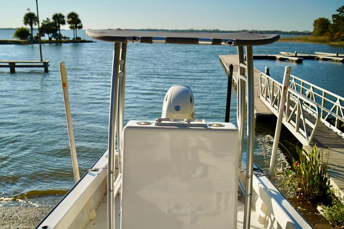 1970 Aquasport 222 Flatback boat docked by a serene lake under clear skies.