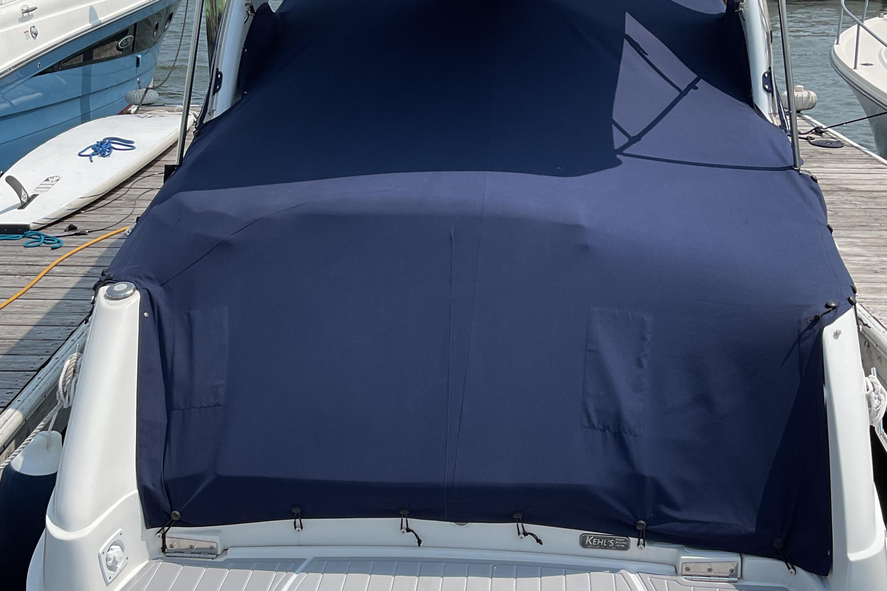 2013 Rinker 290 Express Cruiser with navy cover docked at marina.