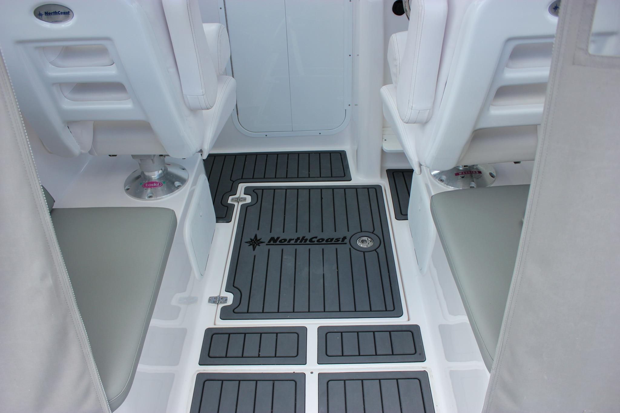 Interior of 2022 NorthCoast 235 Cabin boat with cushioned seating and branded flooring.