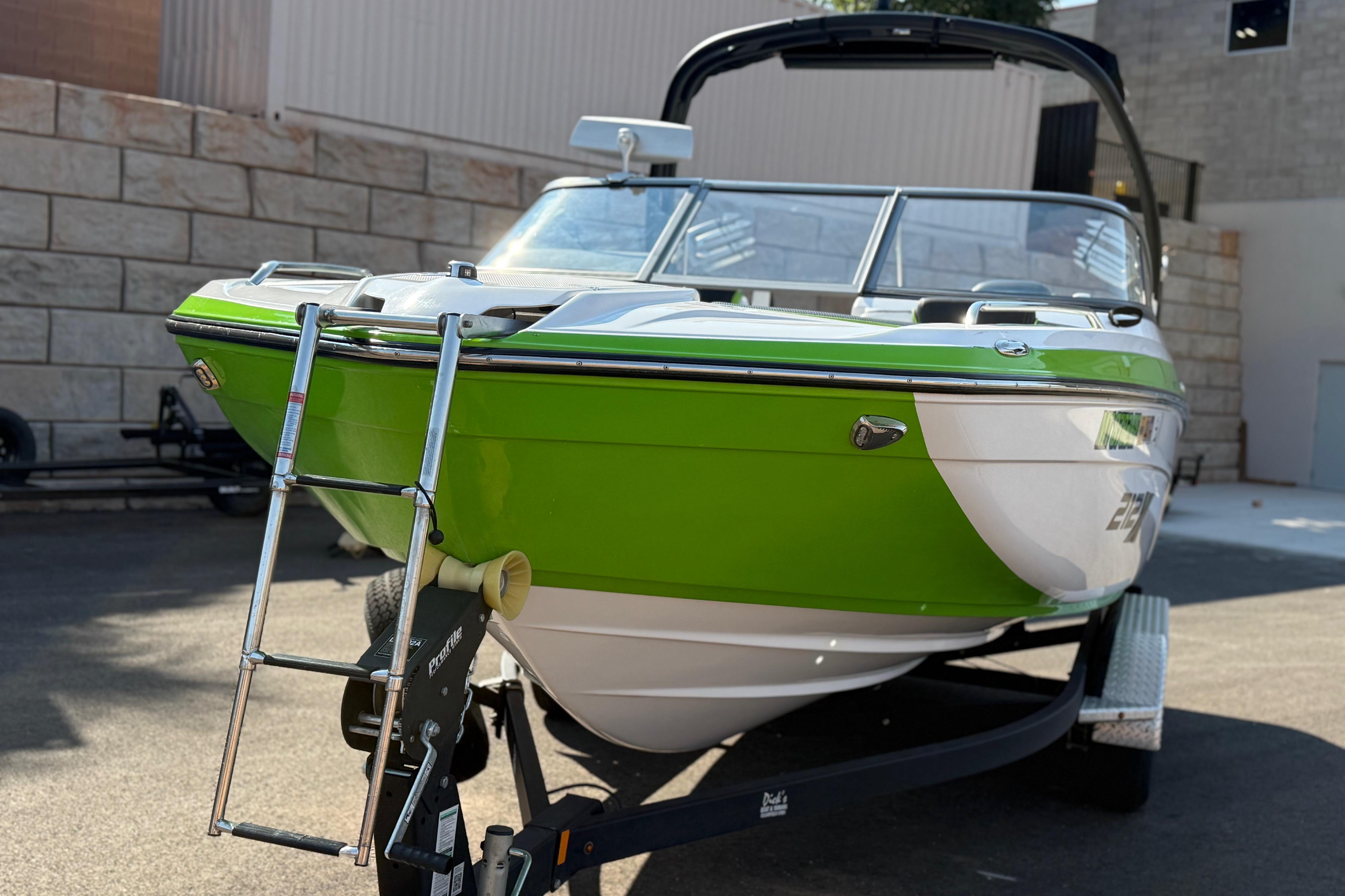 2022 Yamaha Boats 212XE in vibrant green, parked on a trailer, showcasing sleek design.
