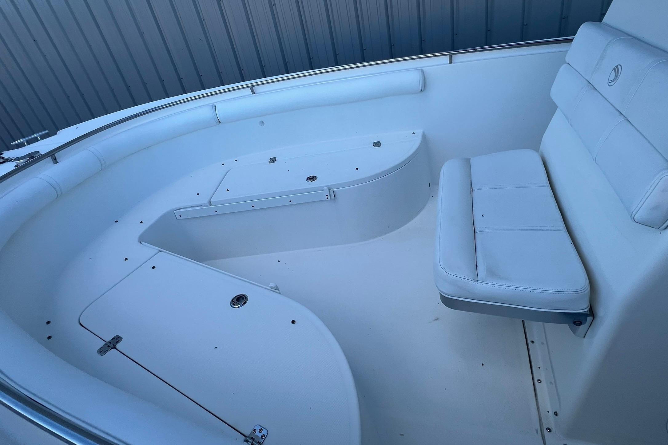 Interior of a 2006 Edgewater 245CC boat, featuring white seating and storage compartments.