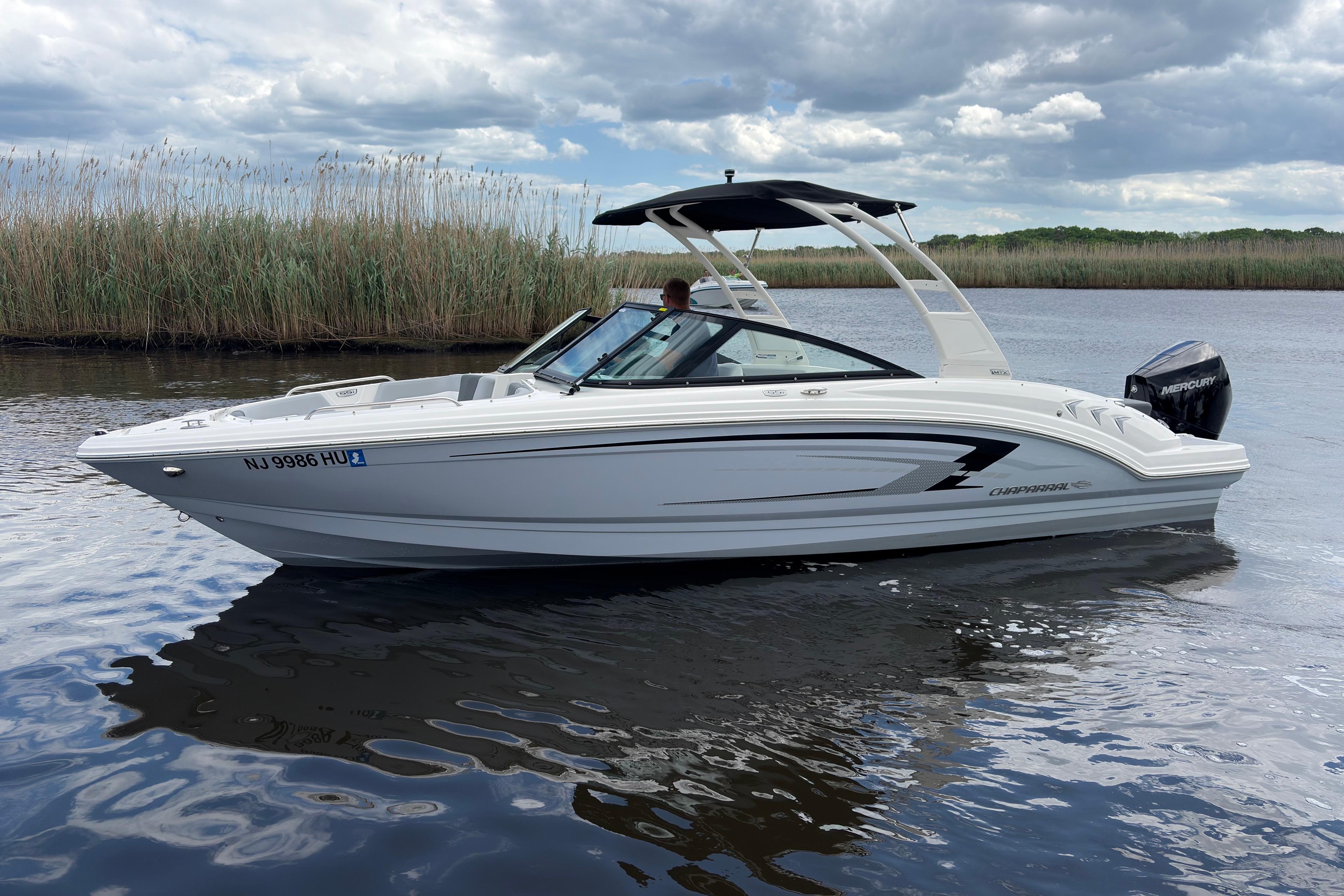 2026 Chaparral 23 SSi OB boat on calm water under cloudy sky.