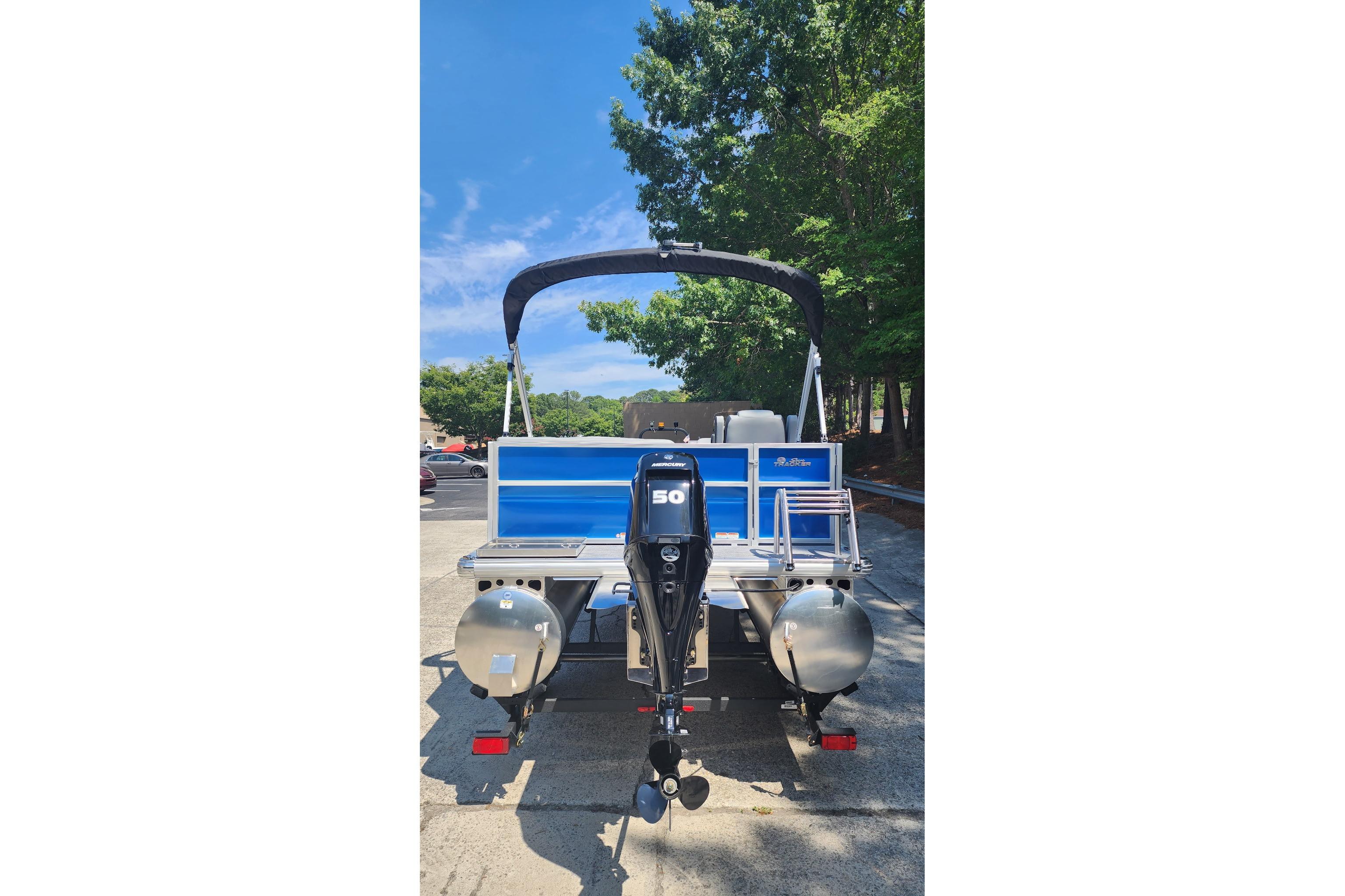 2026 Sun Tracker Party Barge 16 DLX pontoon boat with outboard motor, parked outdoors.