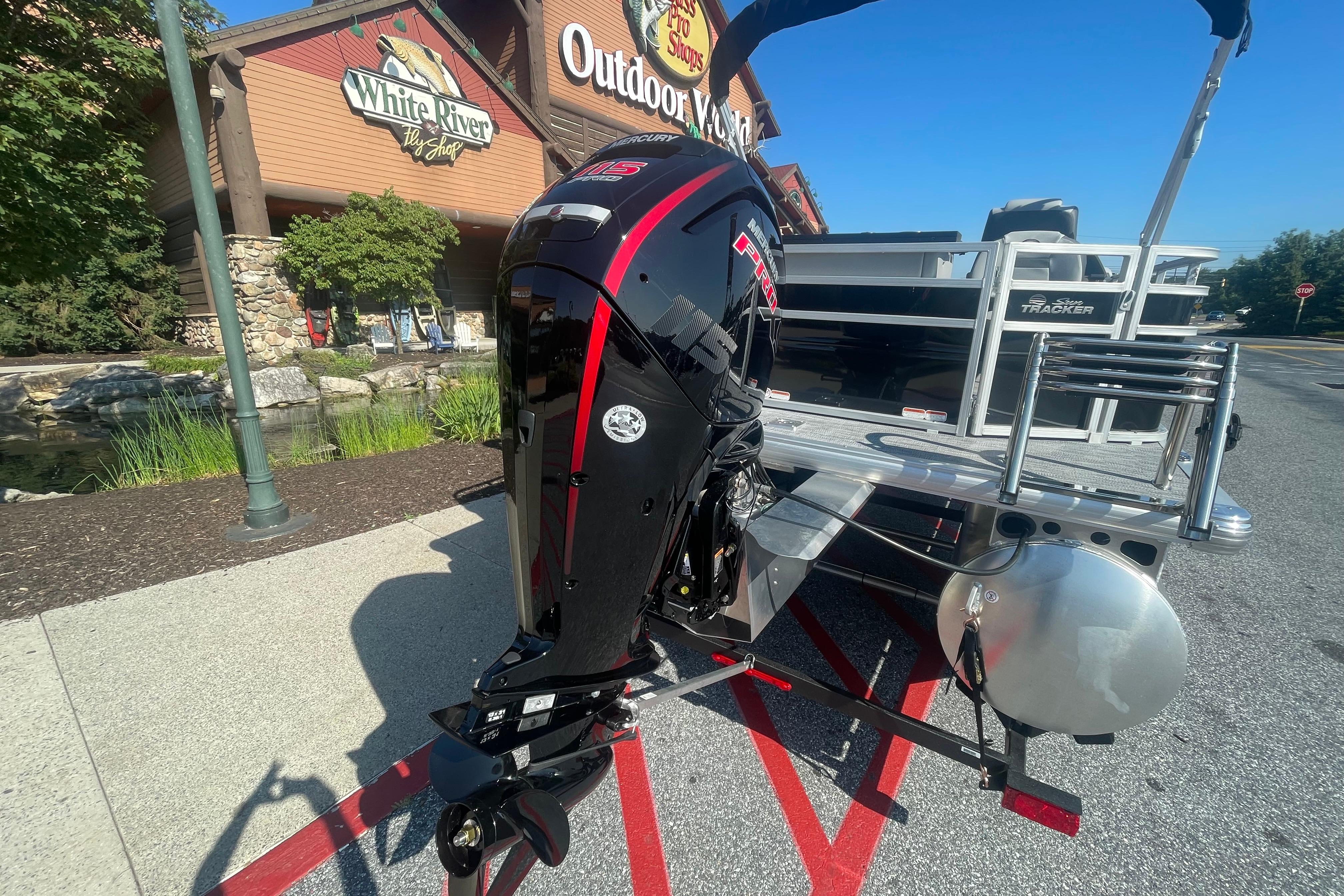 2026 Sun Tracker SportFish 20 DLX pontoon boat with powerful outboard motor, outdoor store backdrop.