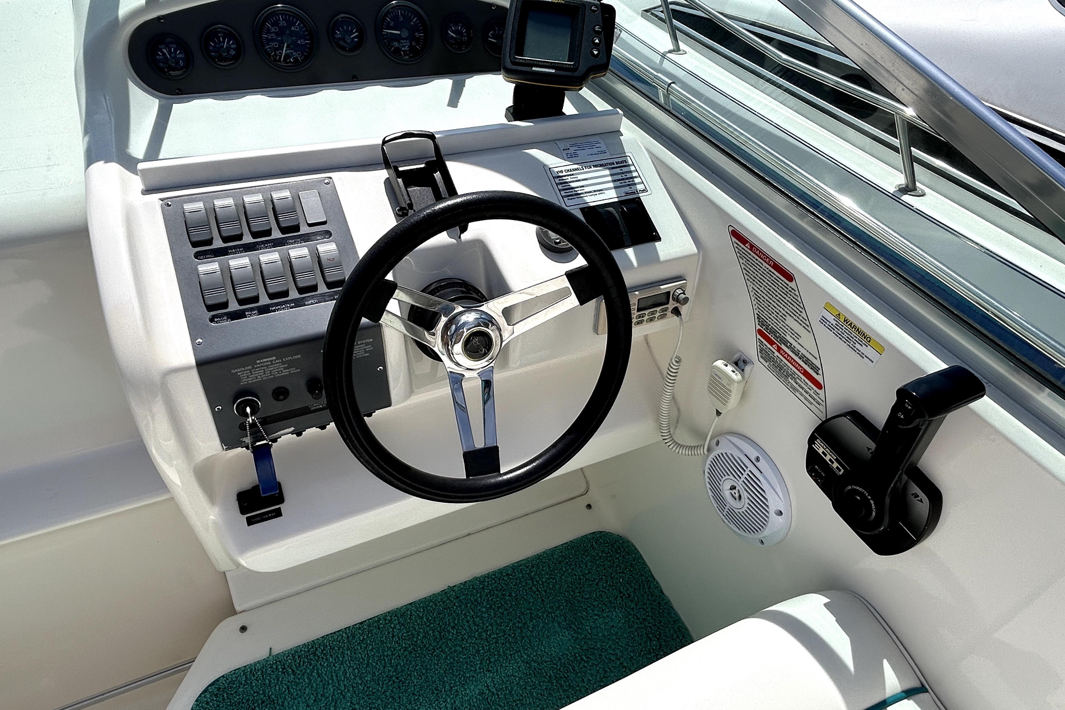 1995 Sea Ray 250 Sundancer helm with steering wheel, controls, and gauges.