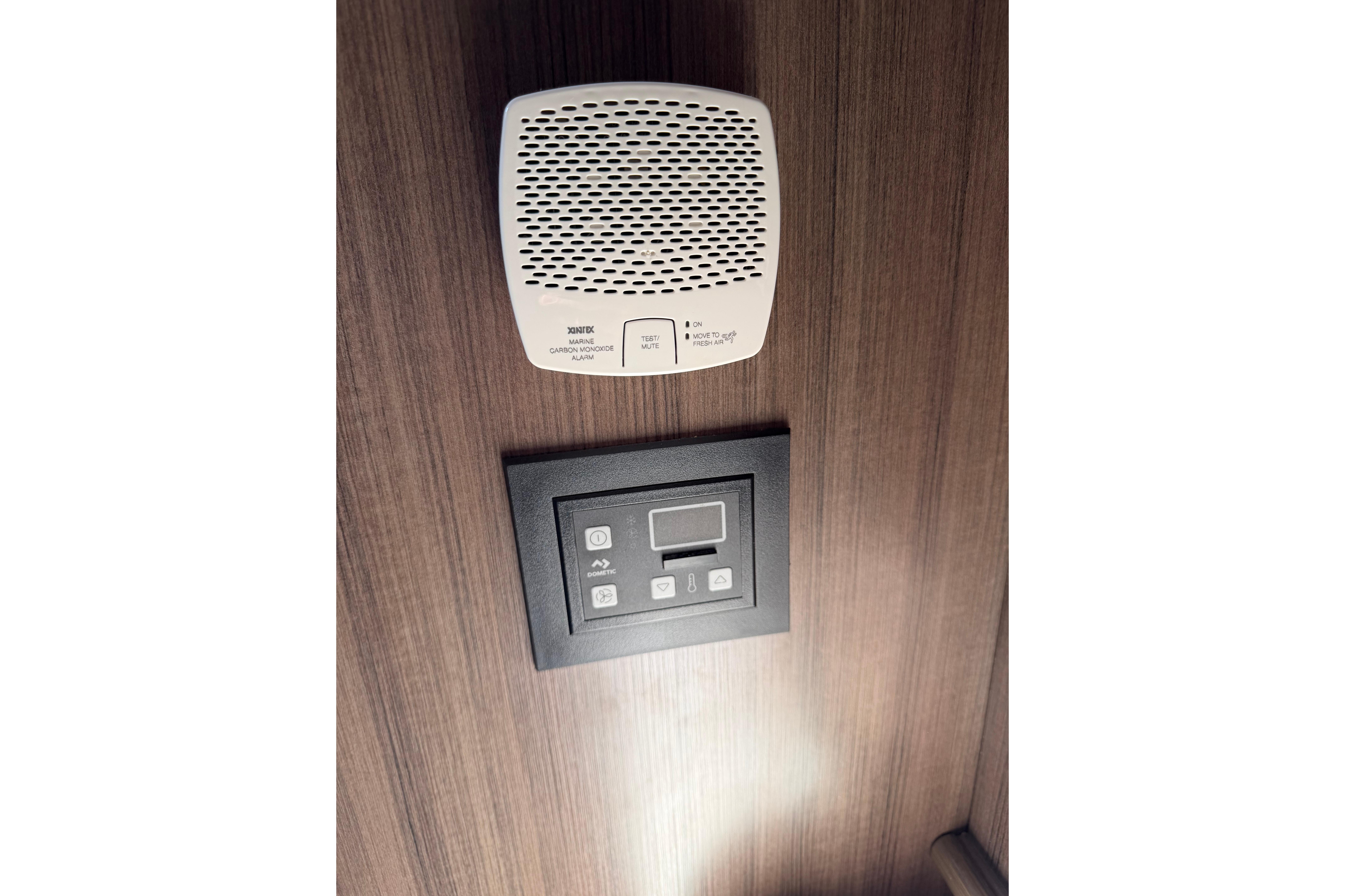 2019 Rinker EX 320 cabin with carbon monoxide alarm and control panel on wooden wall.