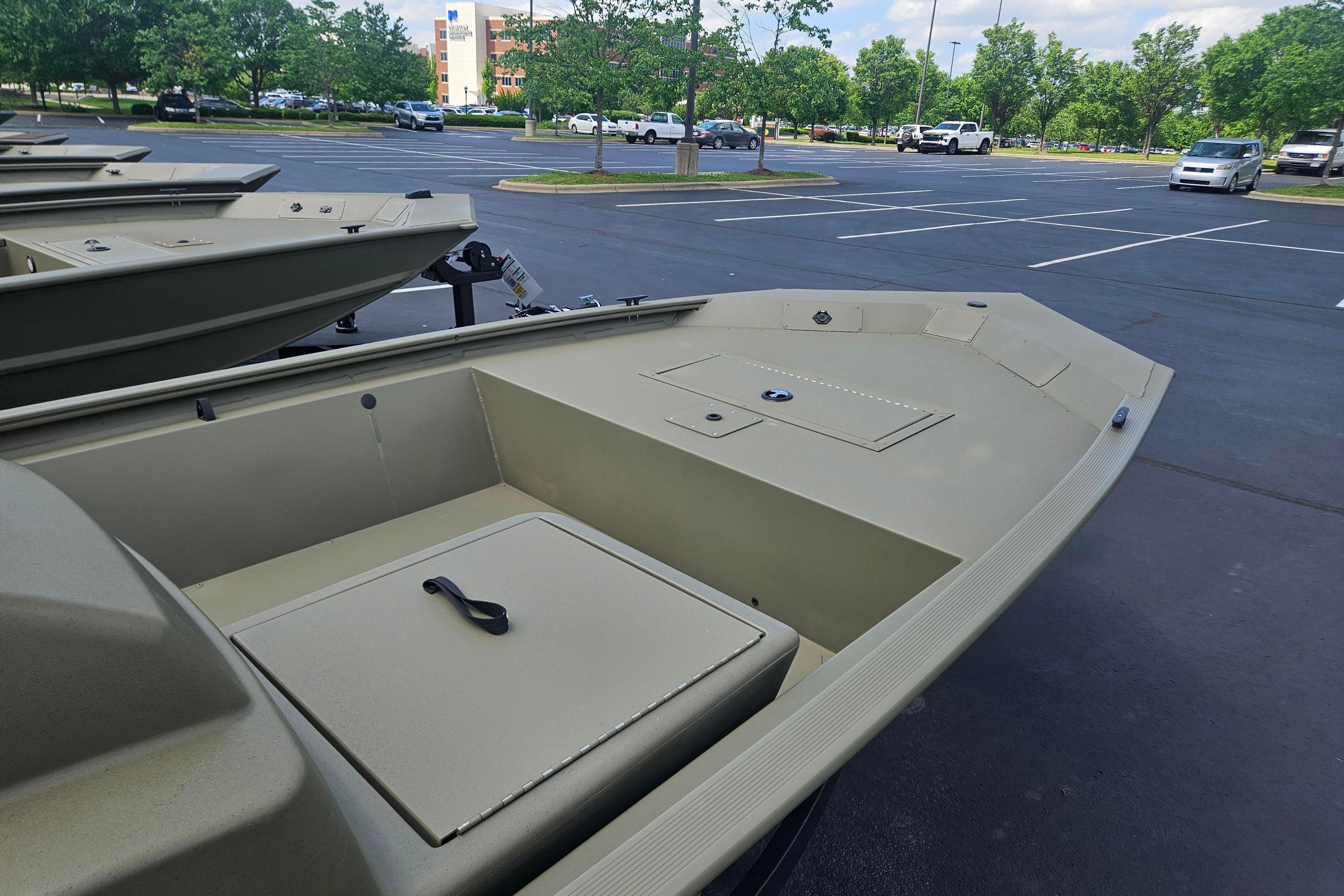 2026 Tracker Grizzly 1648 SC boat in parking lot, showcasing spacious interior and storage compartments.