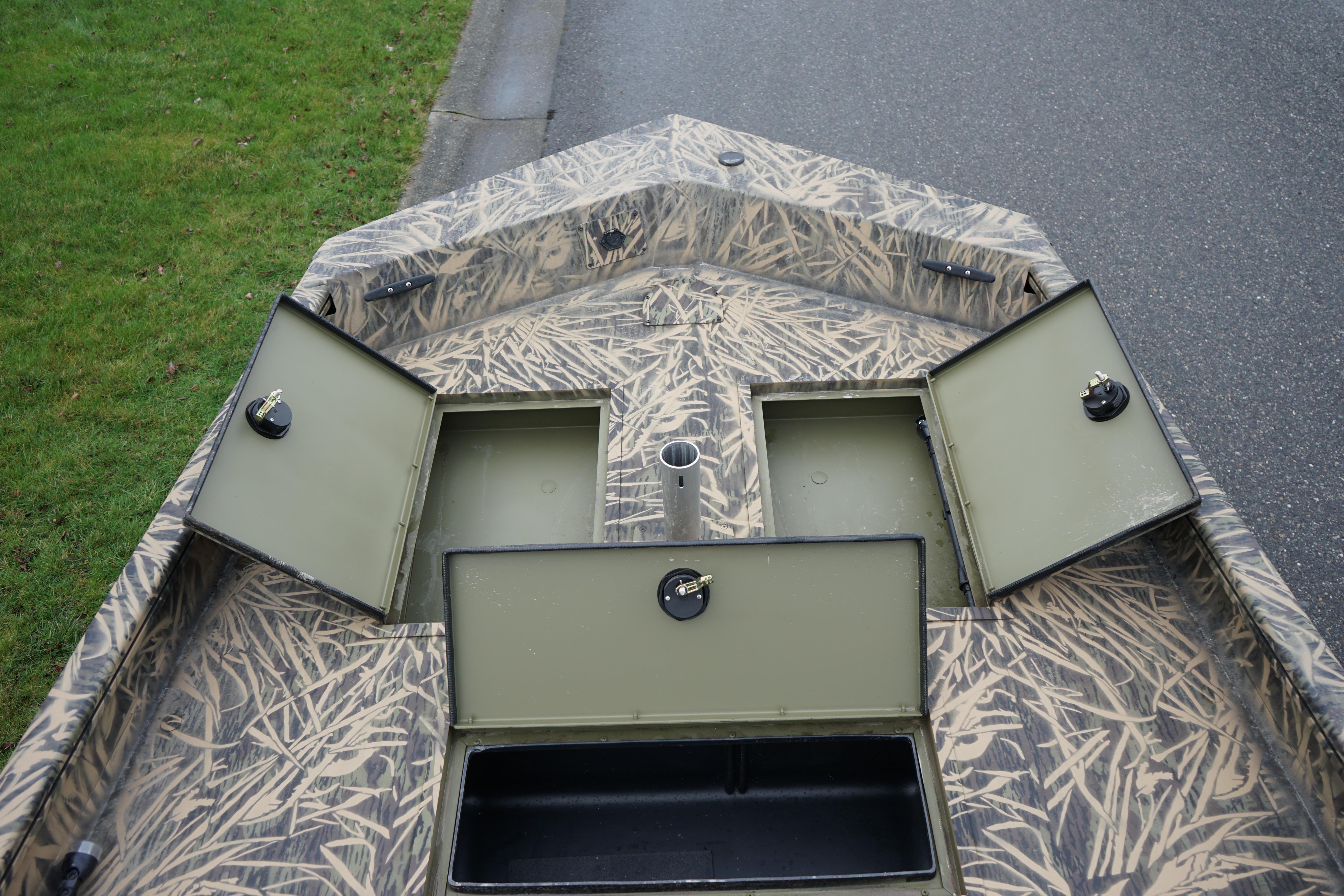 2024 Lund 1760 Predator Tiller boat with open storage compartments and camouflage design.