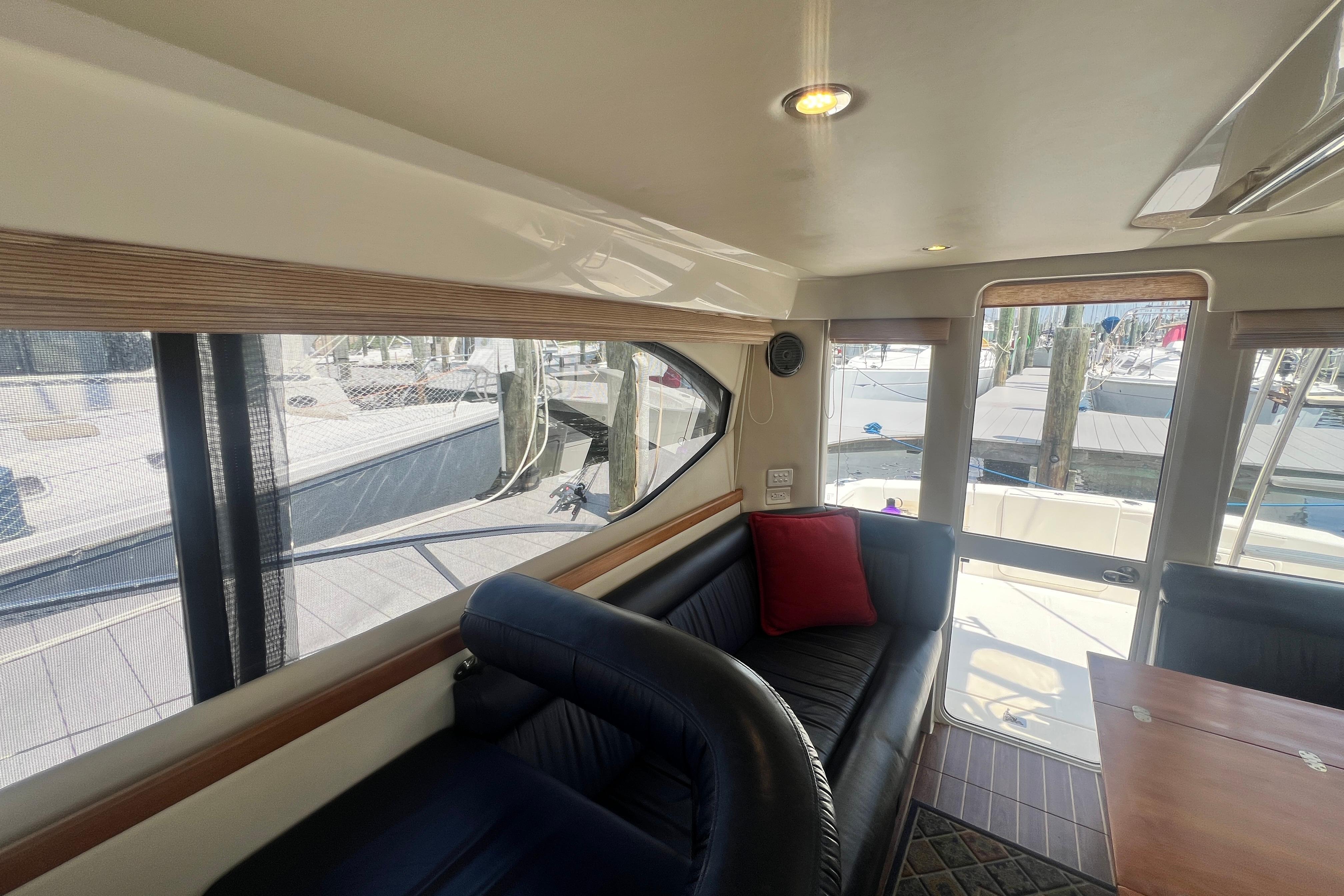 Interior of 2007 Riviera 33 Flybridge yacht with seating and table, dock view.
