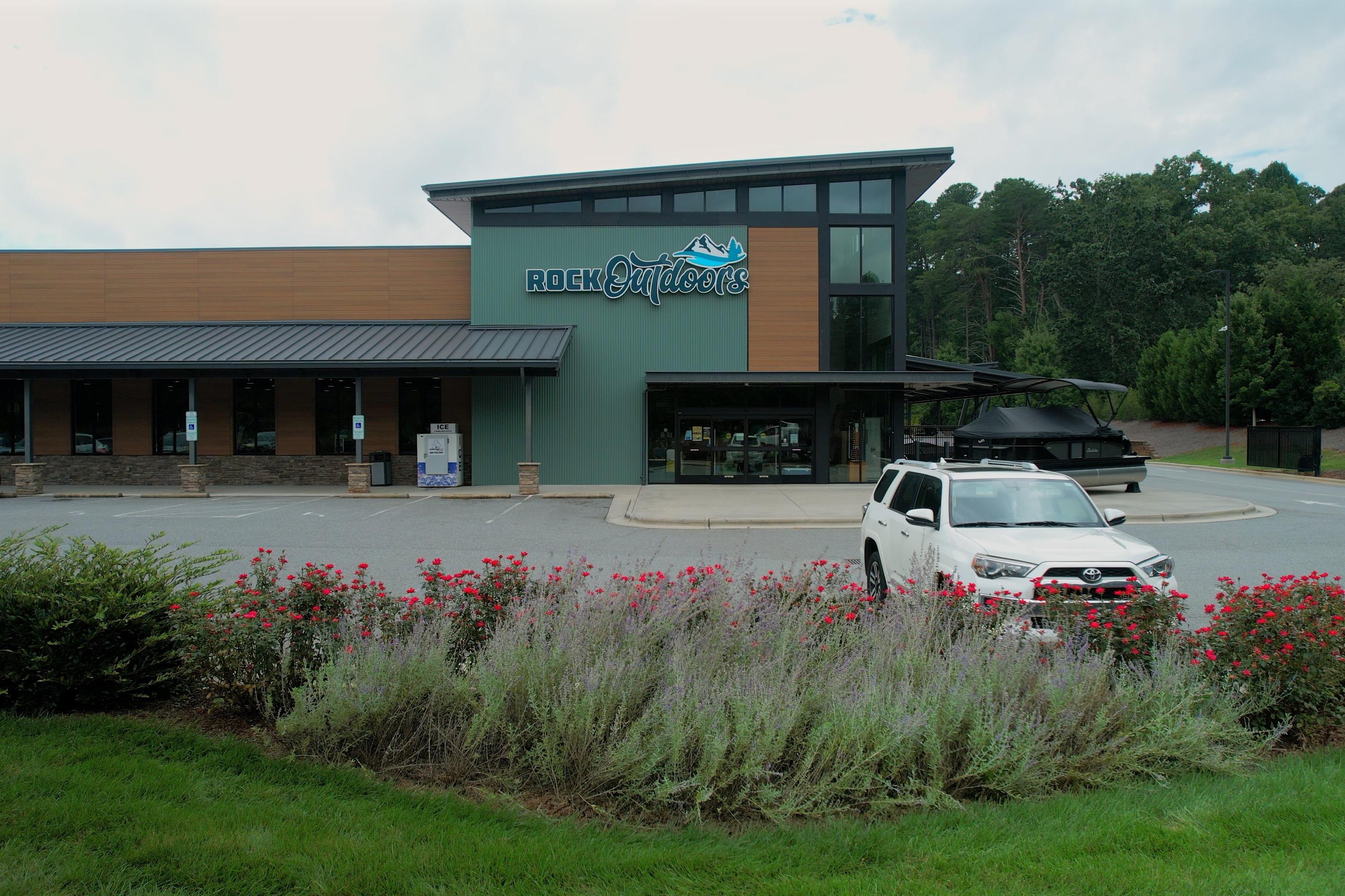 Outdoor store with Barletta Lusso 23UCA boat and white SUV in parking lot.
