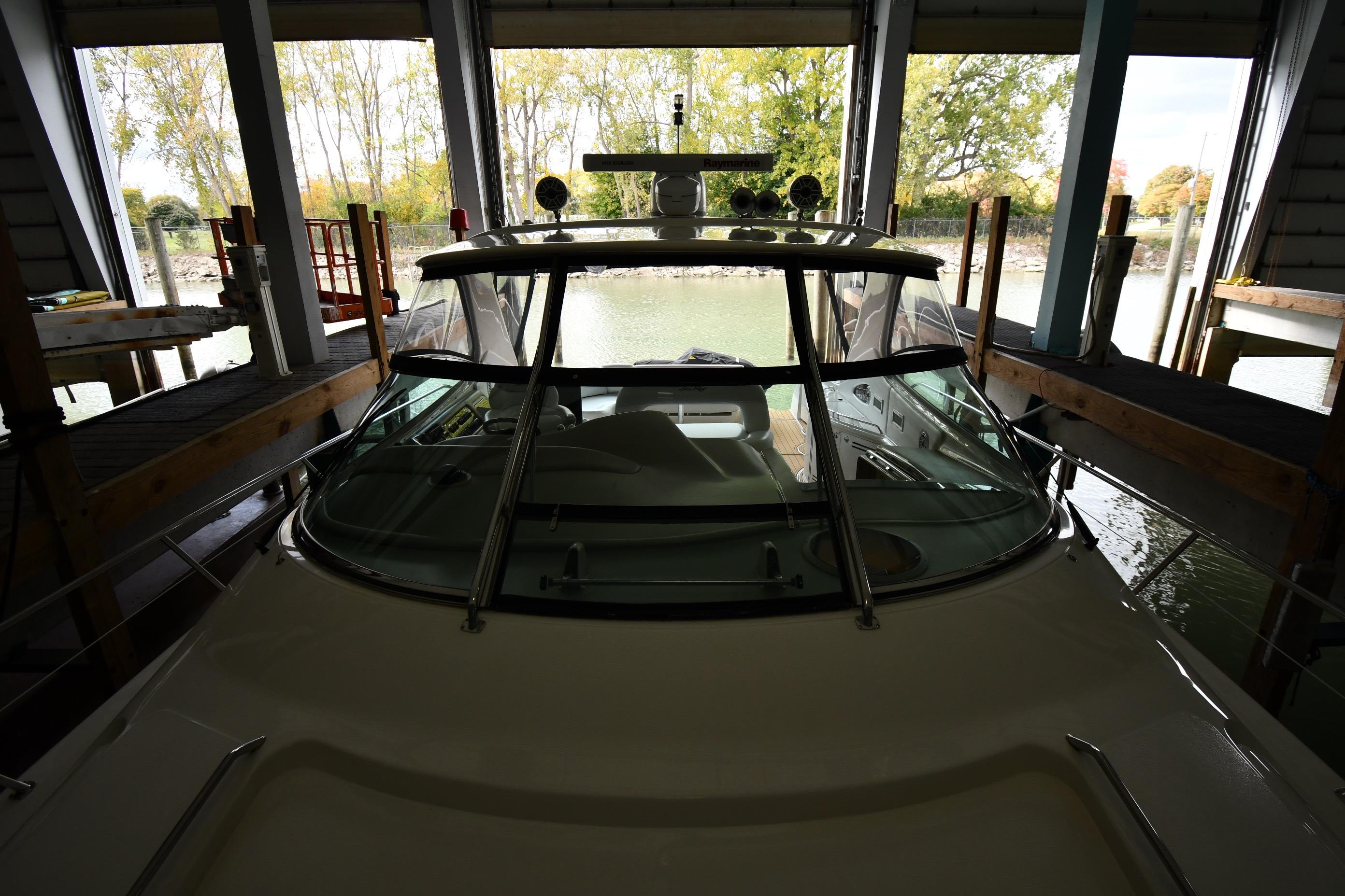 2001 Sea Ray 540 Sundancer docked in a covered marina with scenic background.