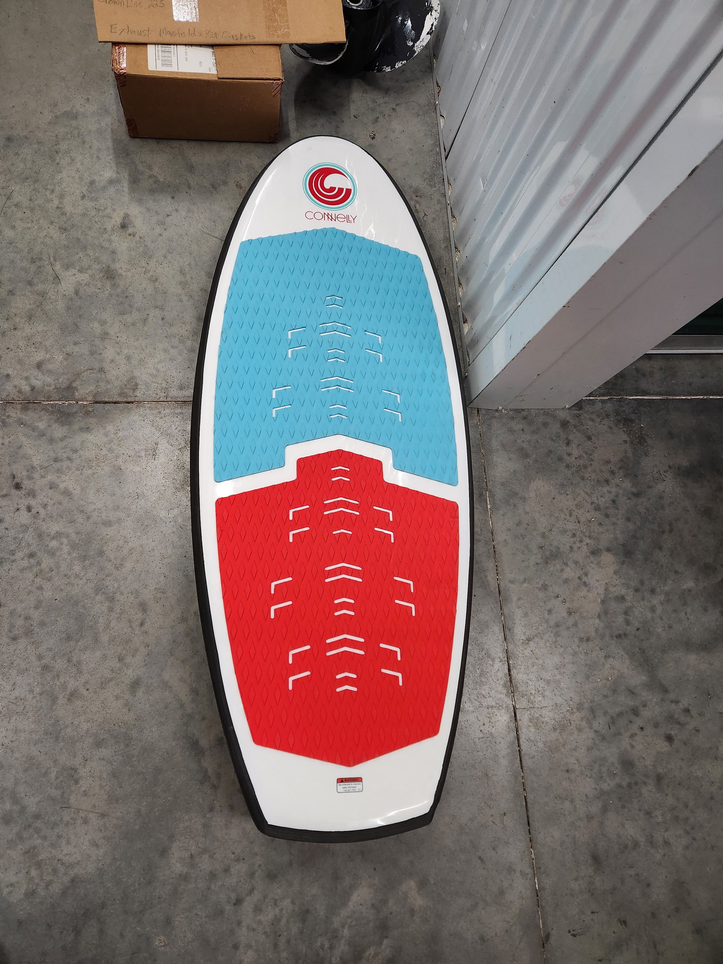 Connelly wakesurf board with blue and red design on concrete floor.