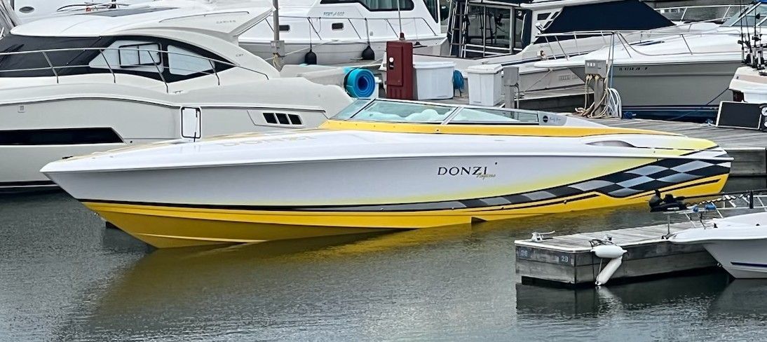 A yellow and white Donzi Daytona 45 ZX boat is docked in the water.