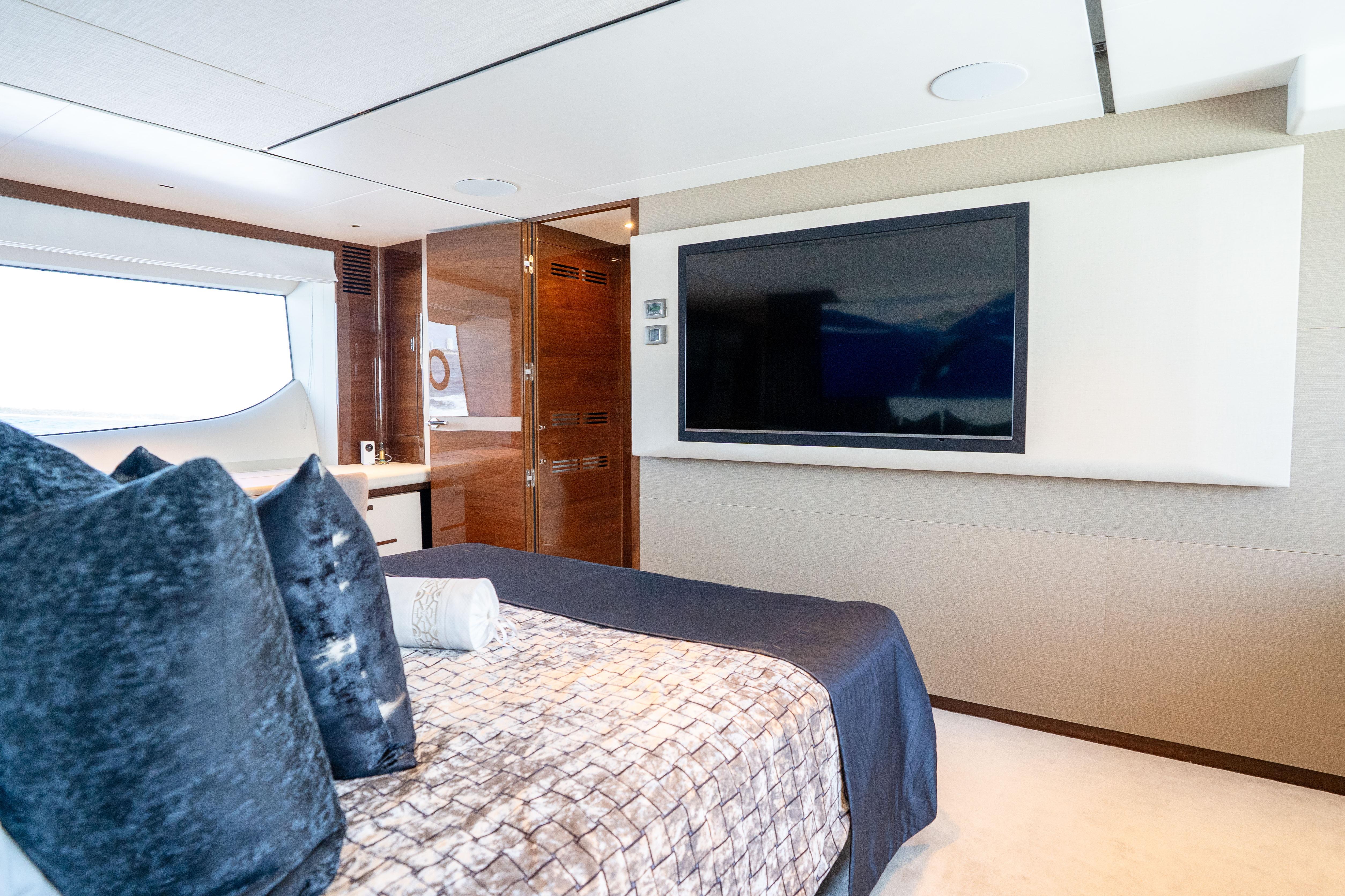 Luxurious bedroom interior of 2020 Princess Y85 yacht with modern decor and large TV.