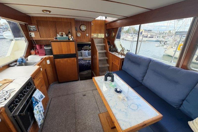 1987 Tollycraft 34 Sundeck Motor Yacht interior with kitchen, seating, and marina view.