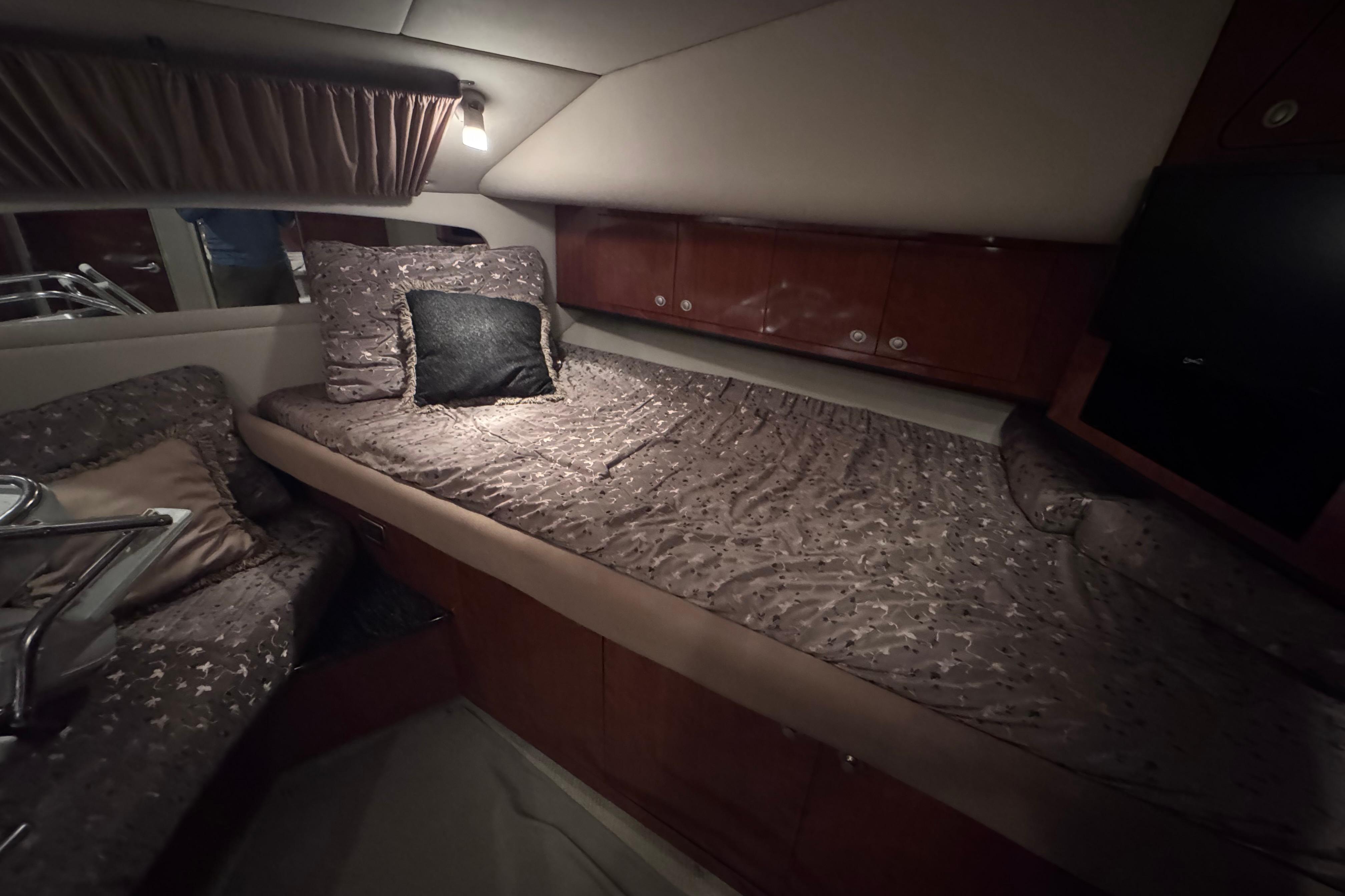 Luxurious cabin interior of 2004 Sea Ray 390 Motor Yacht with cozy bedding and ambient lighting.