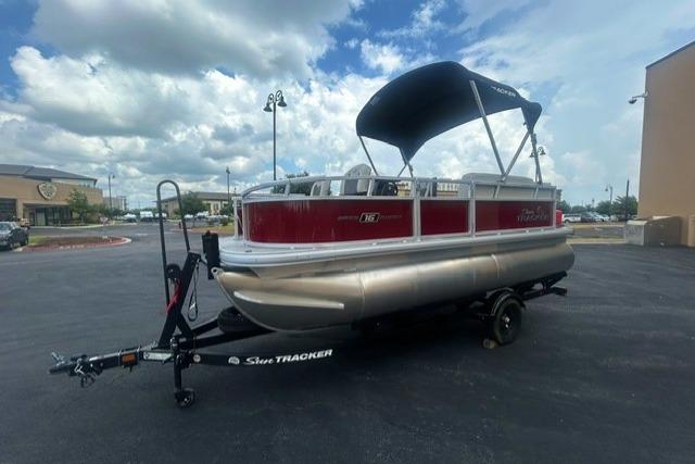 2026 Sun Tracker Bass Buggy 16 XL Select pontoon boat on trailer, parked outdoors.