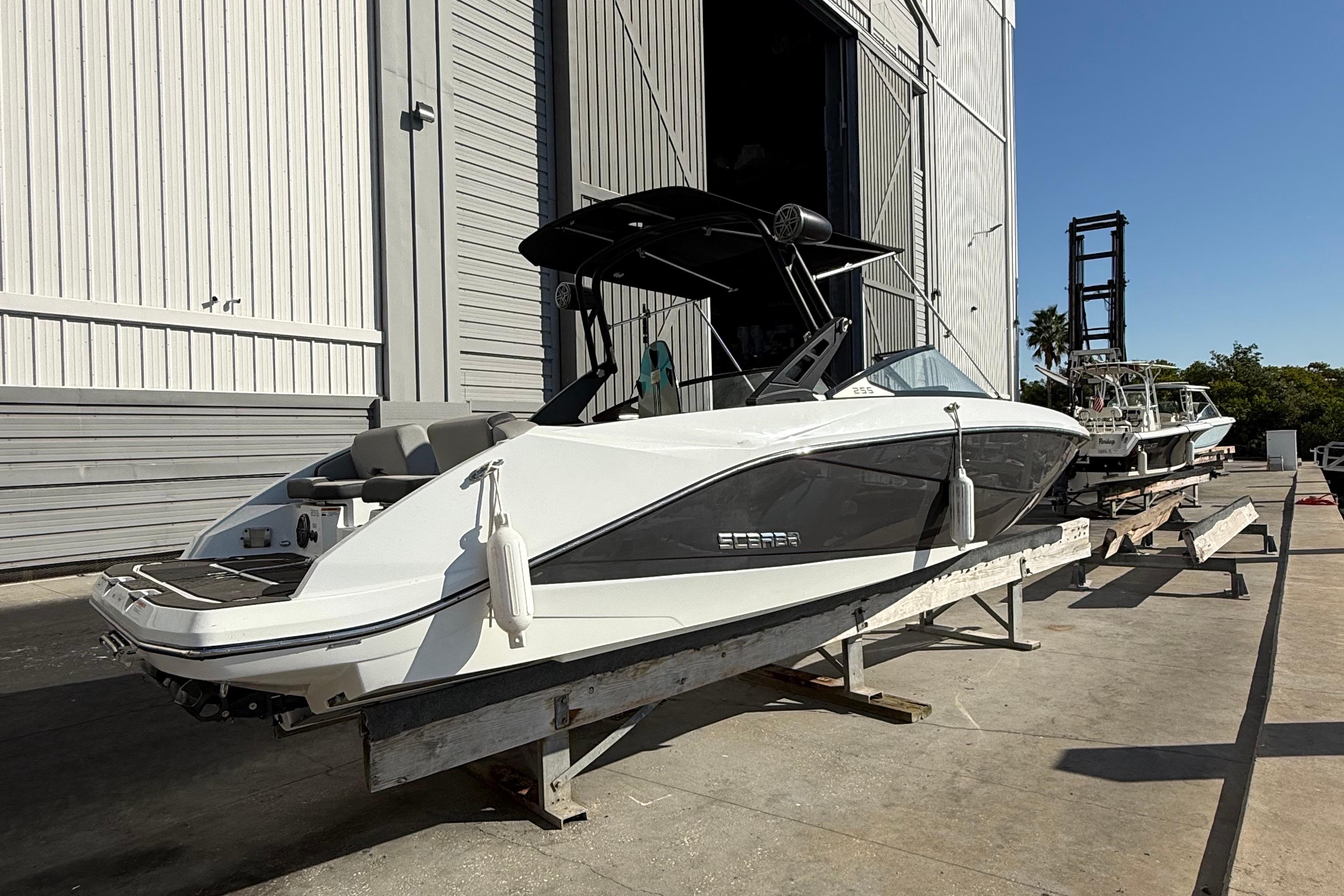 2021 Scarab 255 ID boat on trailer outside a large warehouse.