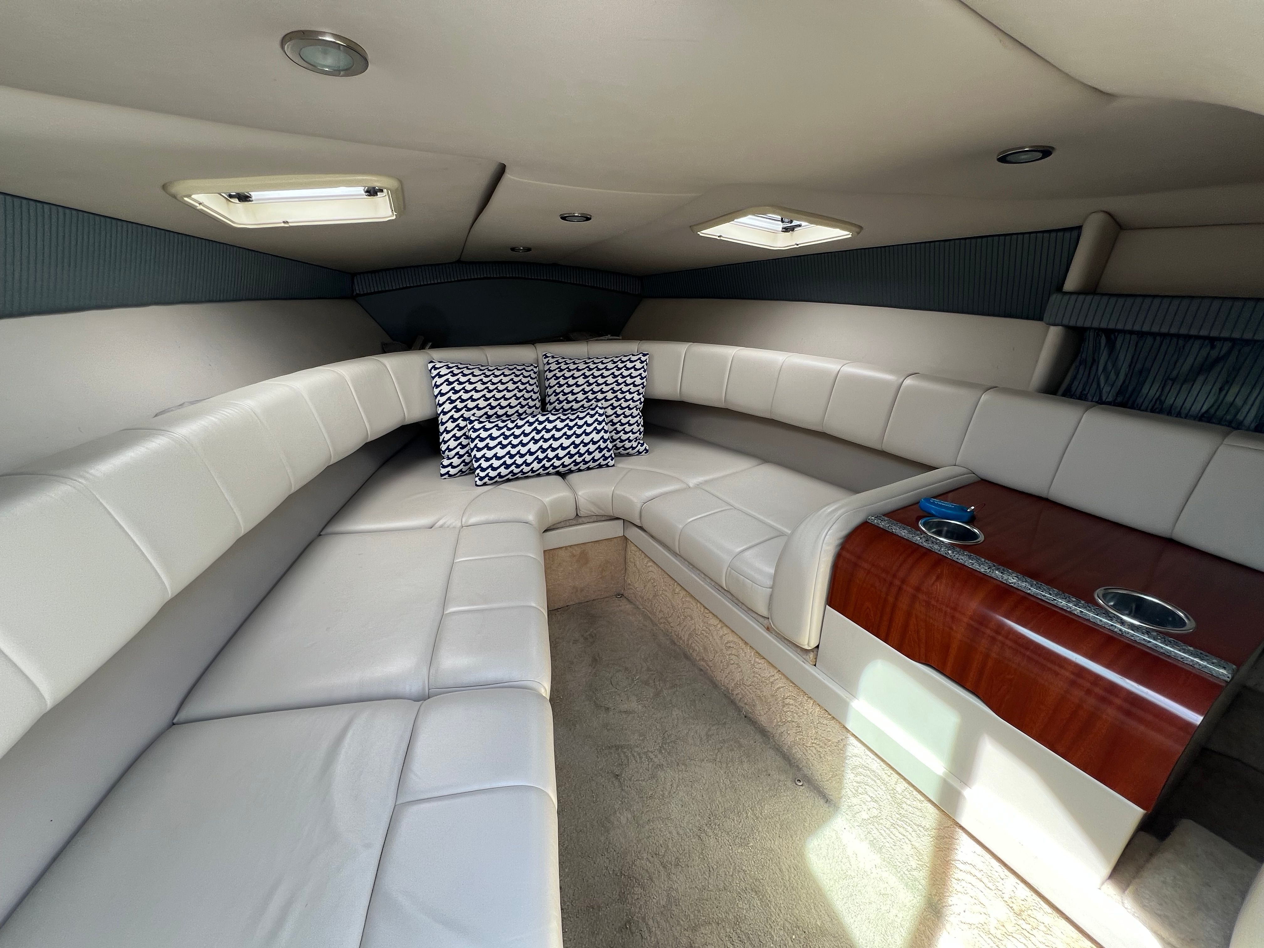 Interior of a 2005 Formula 260 Sun Sport with cream upholstery and a wooden table.