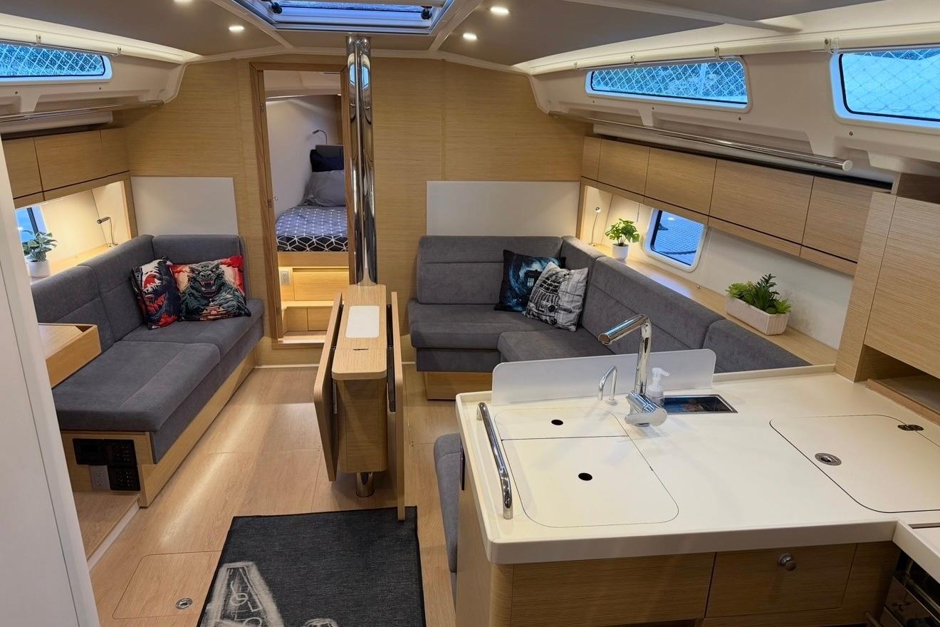Modern interior of 2022 Hanse 418 yacht with cozy seating and sleek kitchen area.