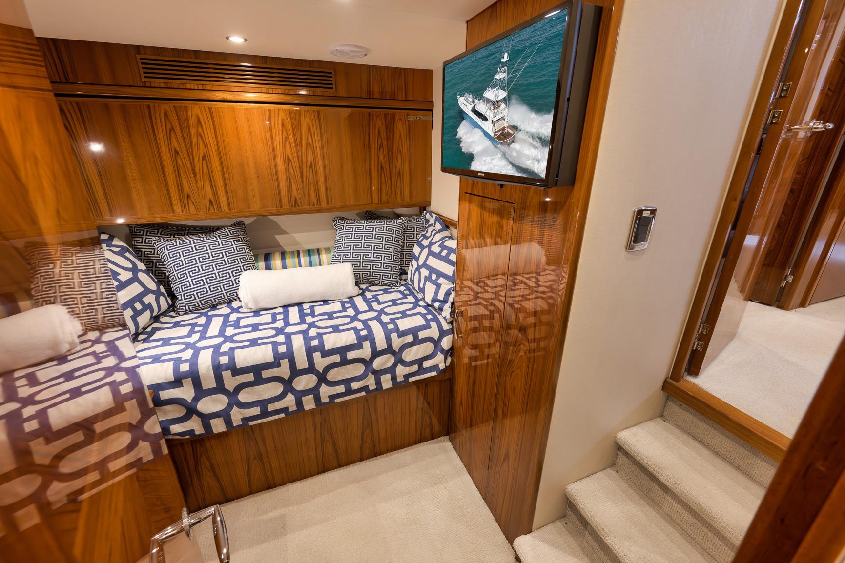 Luxurious cabin interior of 2015 Hatteras GT70 yacht with patterned bedding and wall-mounted TV.