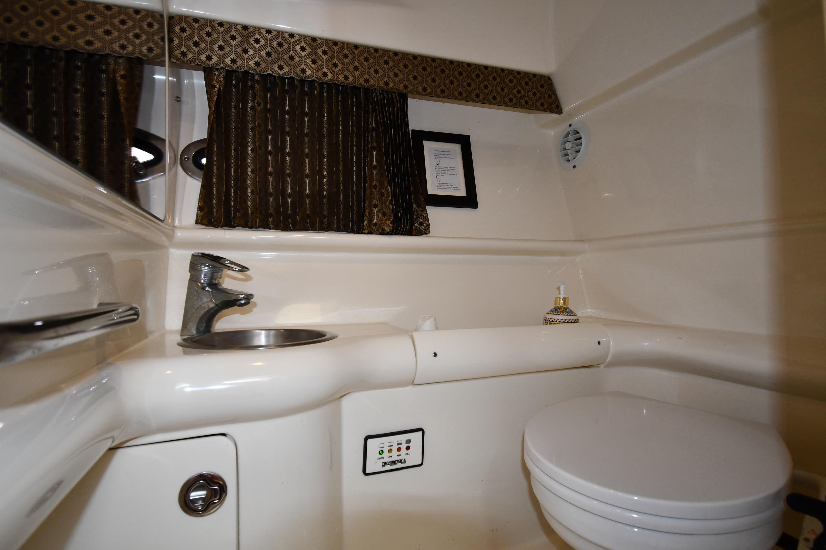 2004 Formula 330 Sun Sport bathroom with sink, toilet, and decorative curtains.
