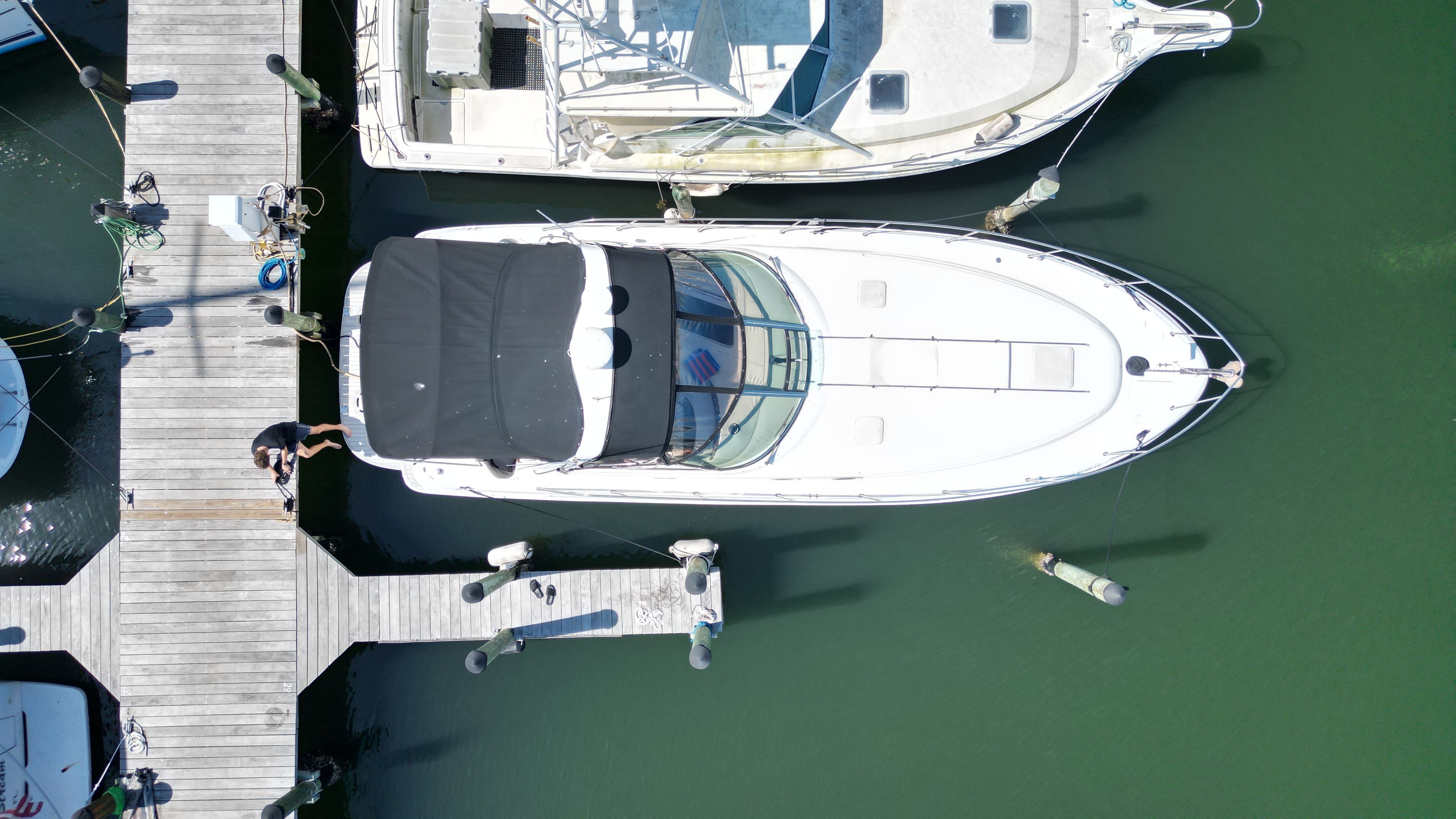 A white boat is docked in a marina, surrounded by other boats and a pier.