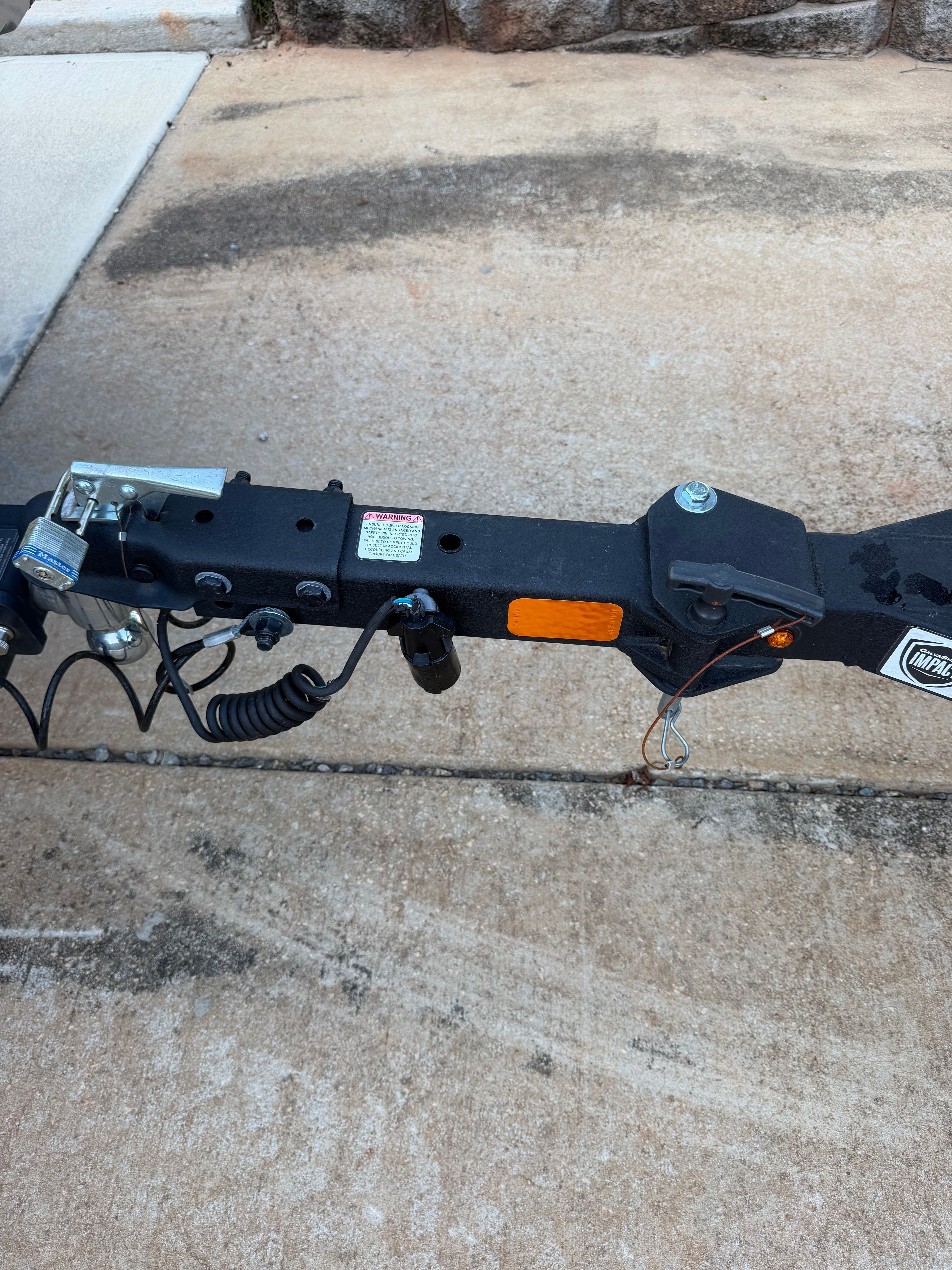 Close-up of a boat trailer with a black frame and cables on a concrete surface.