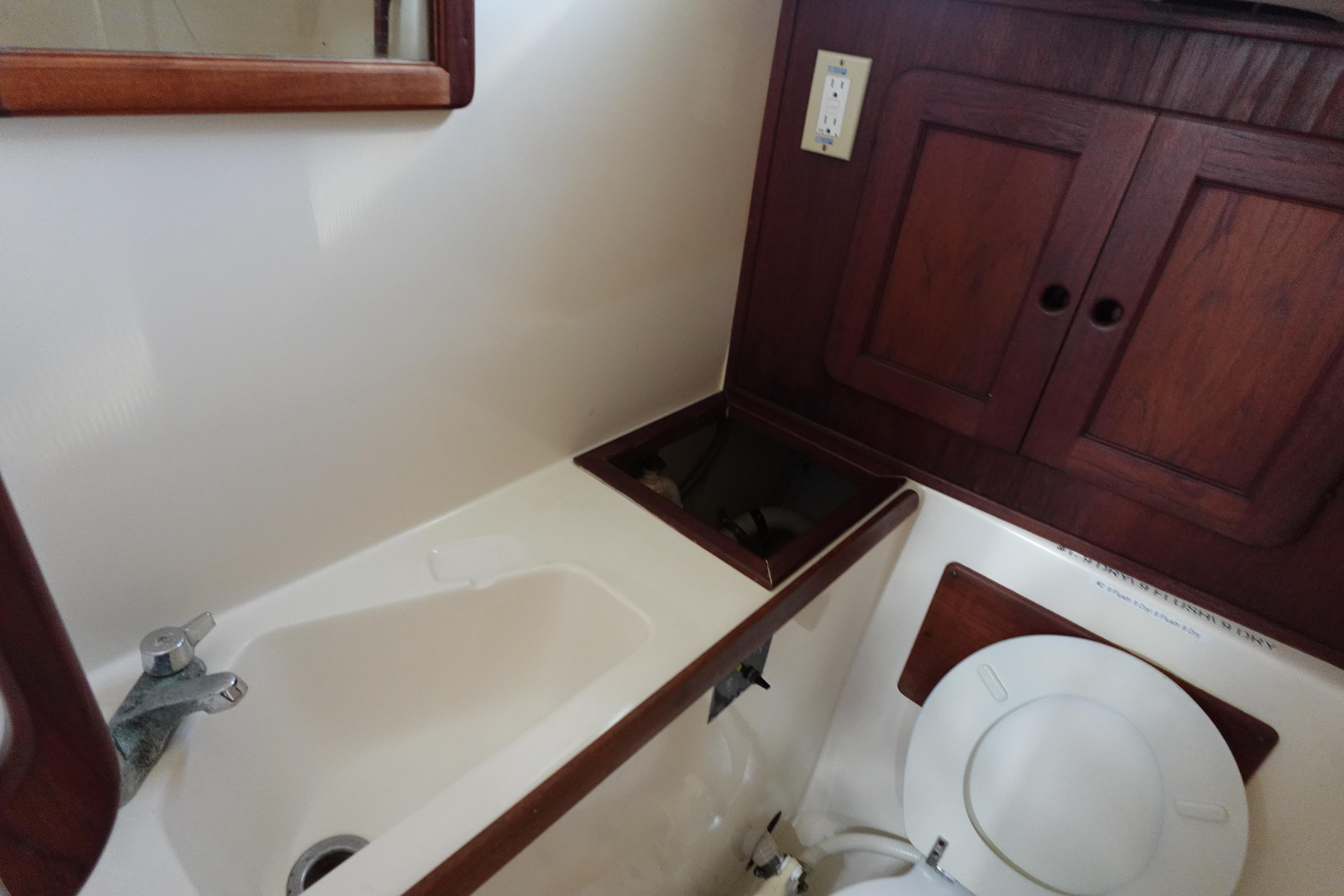 1982 Morgan 383 yacht bathroom with sink, toilet, and wooden cabinets.