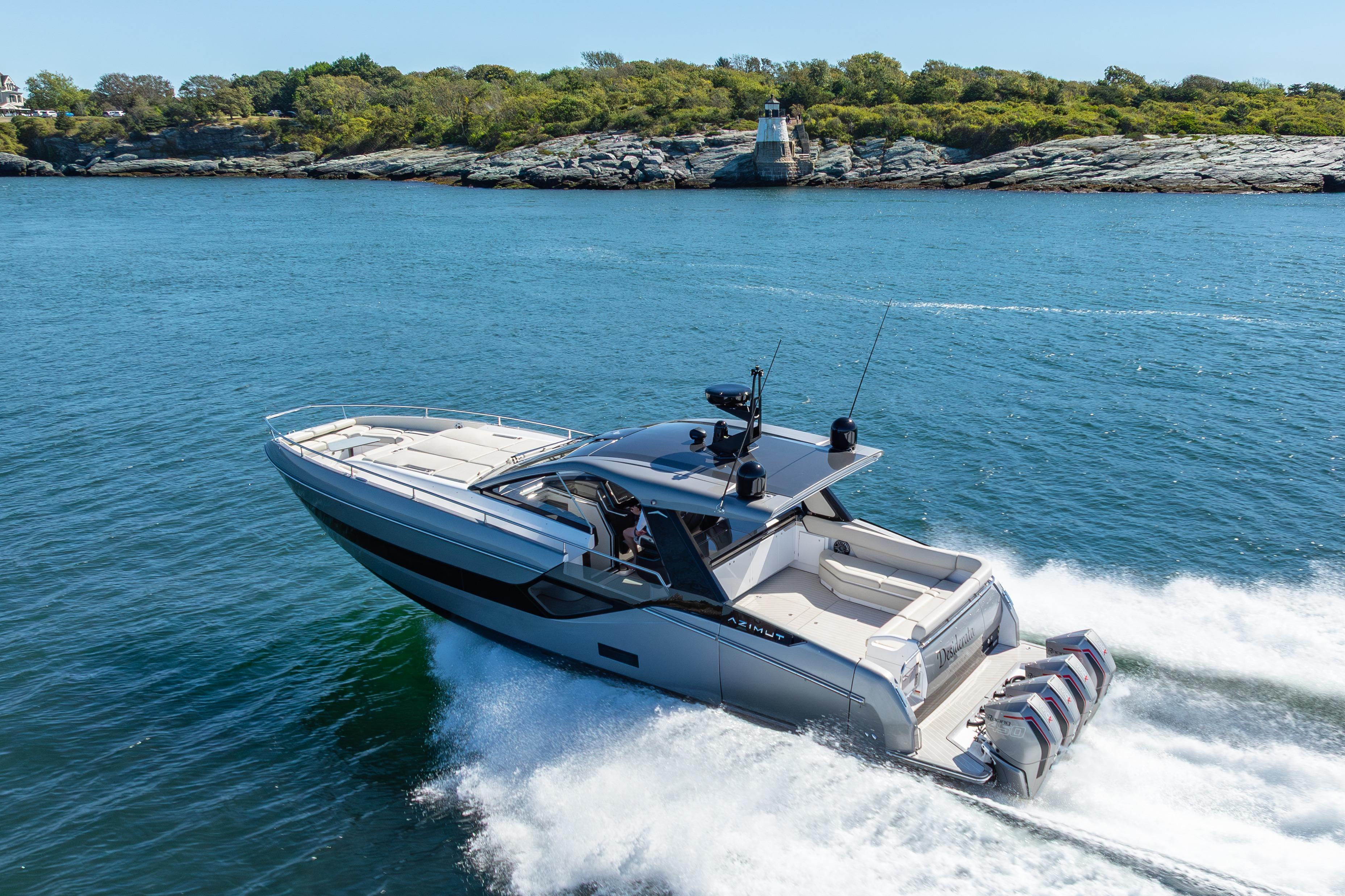 2023 Azimut Verve 47 yacht cruising on blue water near rocky shoreline.