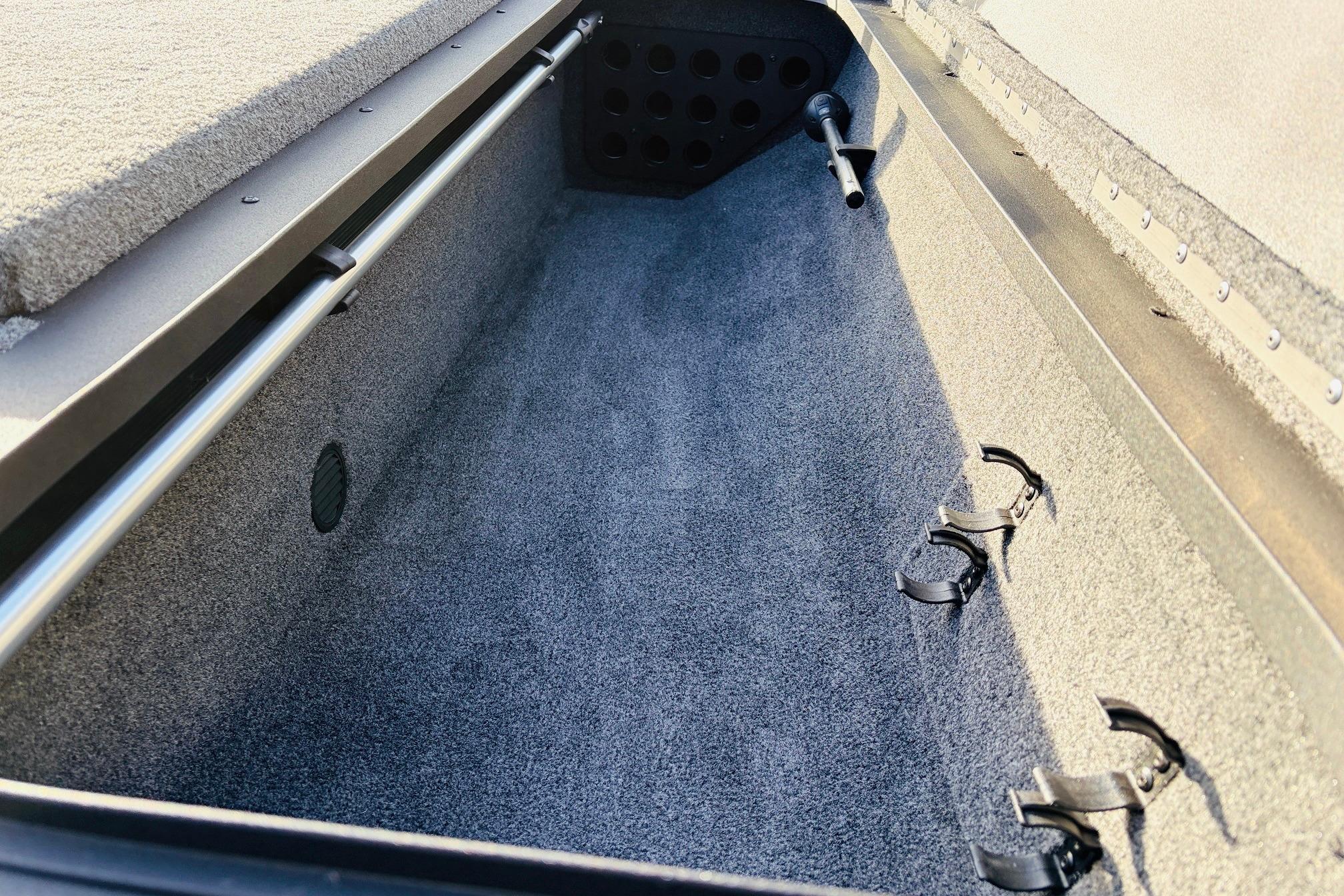 2025 Tracker Savage 215 boat interior storage compartment with carpeted finish and secure rod holders.