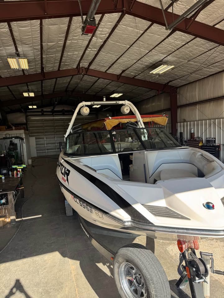 A 2015 Moomba Mojo boat is in a warehouse. It features a modern design and a trailer.