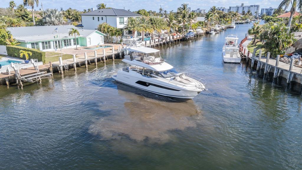 Prestige 520 Flybridge yacht cruising in a scenic canal, 2021 model.