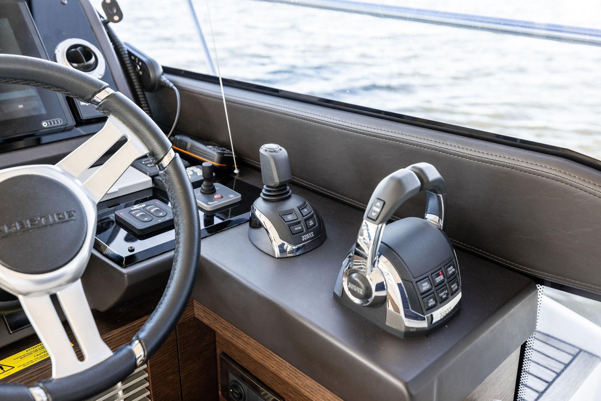 Cockpit controls of a 2019 Prestige 520 yacht, featuring steering wheel and throttle levers.
