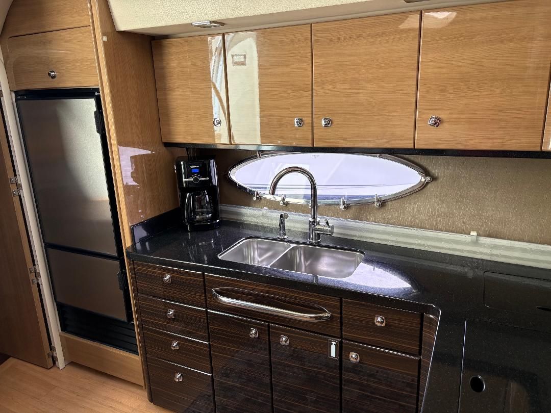 The galley of a 2011 Formula 45 with wood cabinets, stainless steel sink, and a large refrigerator.
