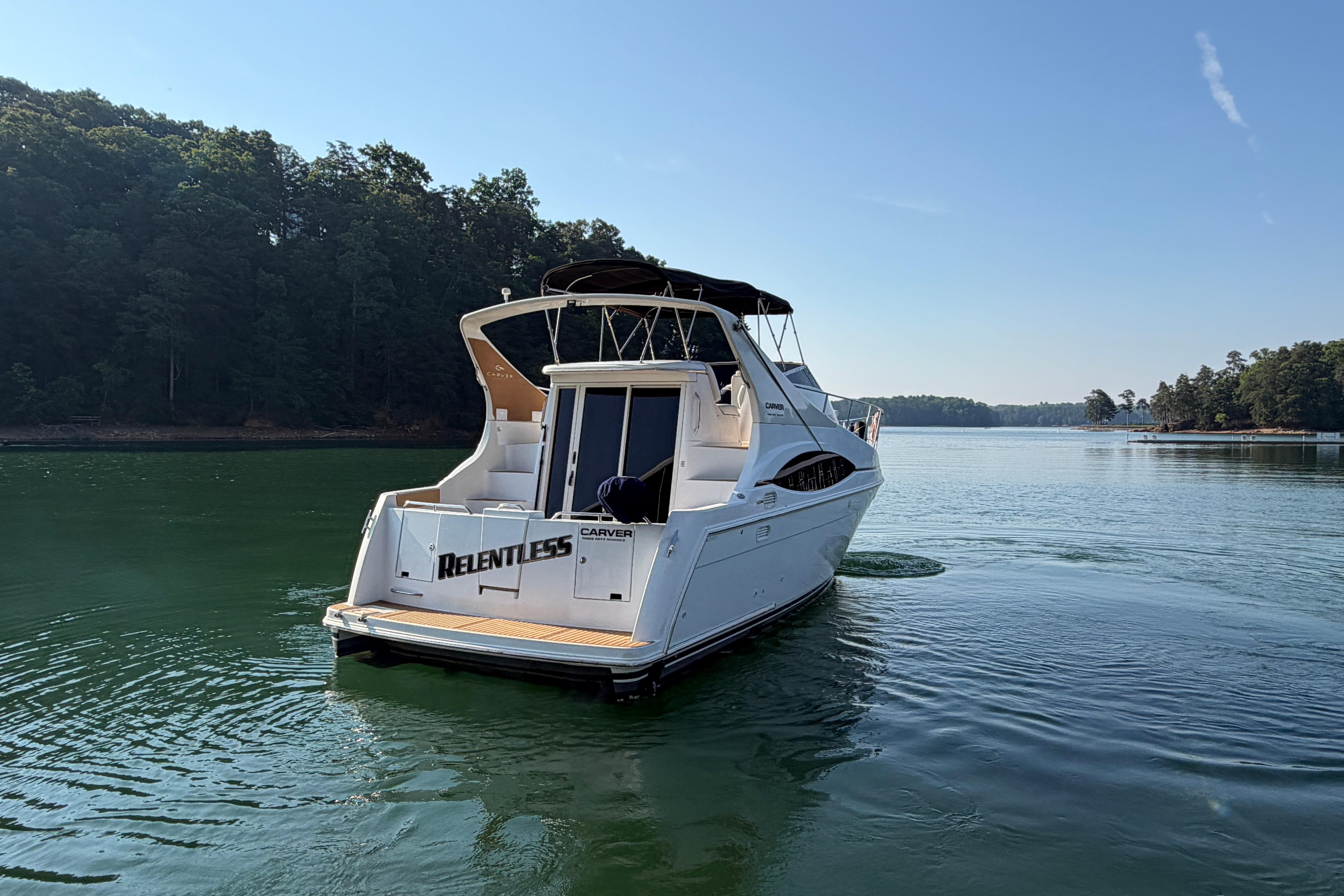 2003 Carver 350 Mariner yacht on serene lake with forested shoreline.
