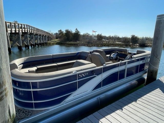 A sleek Bennington pontoon boat docked at a sunny pier, surrounded by calm water.