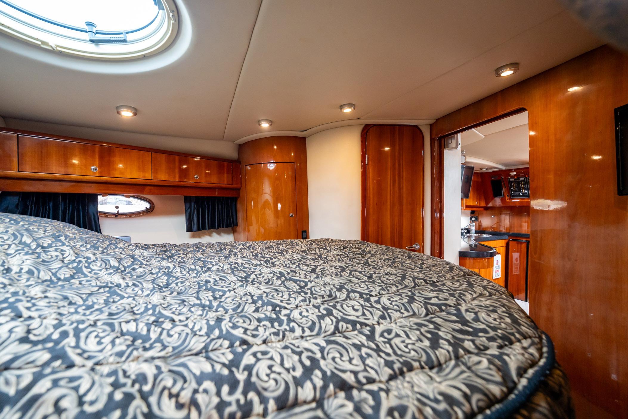 Luxurious interior of 2008 Regal Commodore 4460 yacht with elegant wood finishes and cozy bedding.