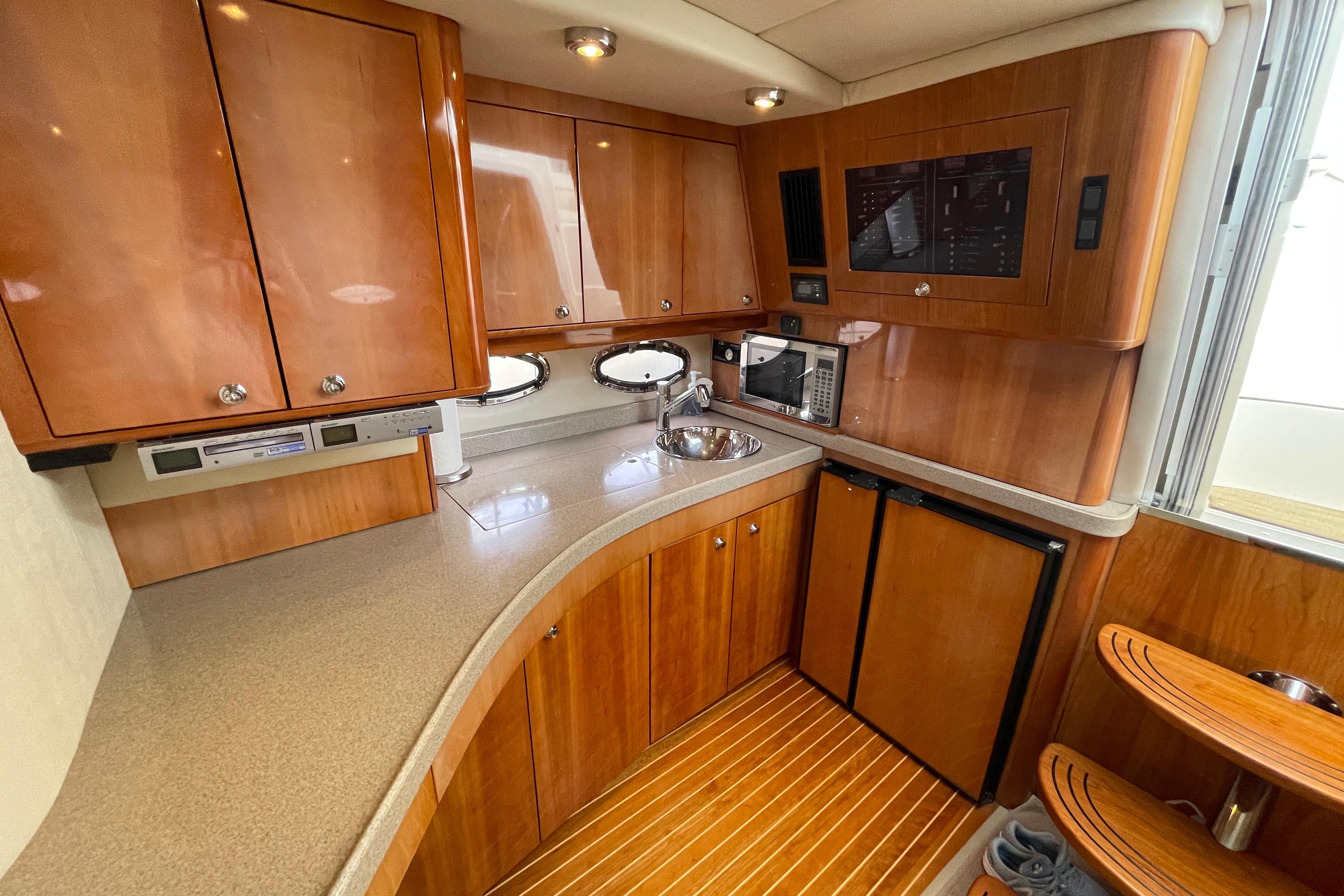 Luxurious 2004 Regal Commodore 4260 yacht kitchen with wood cabinetry and modern appliances.