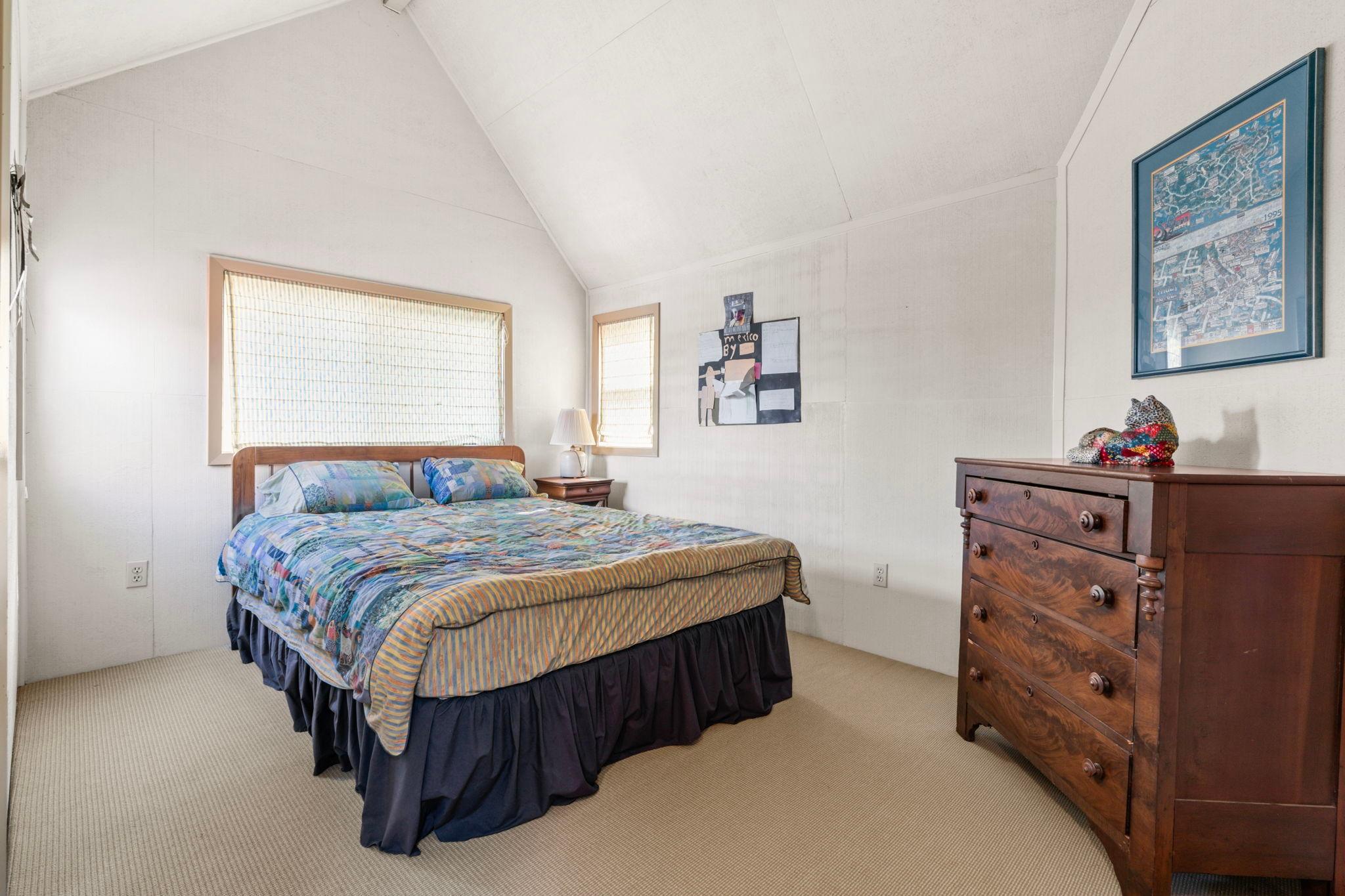Cozy bedroom in a 1976 custom boathouse with colorful bedding and wooden dresser.