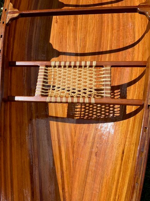 Interior view of a handcrafted cedar strip canoe with a woven seat.