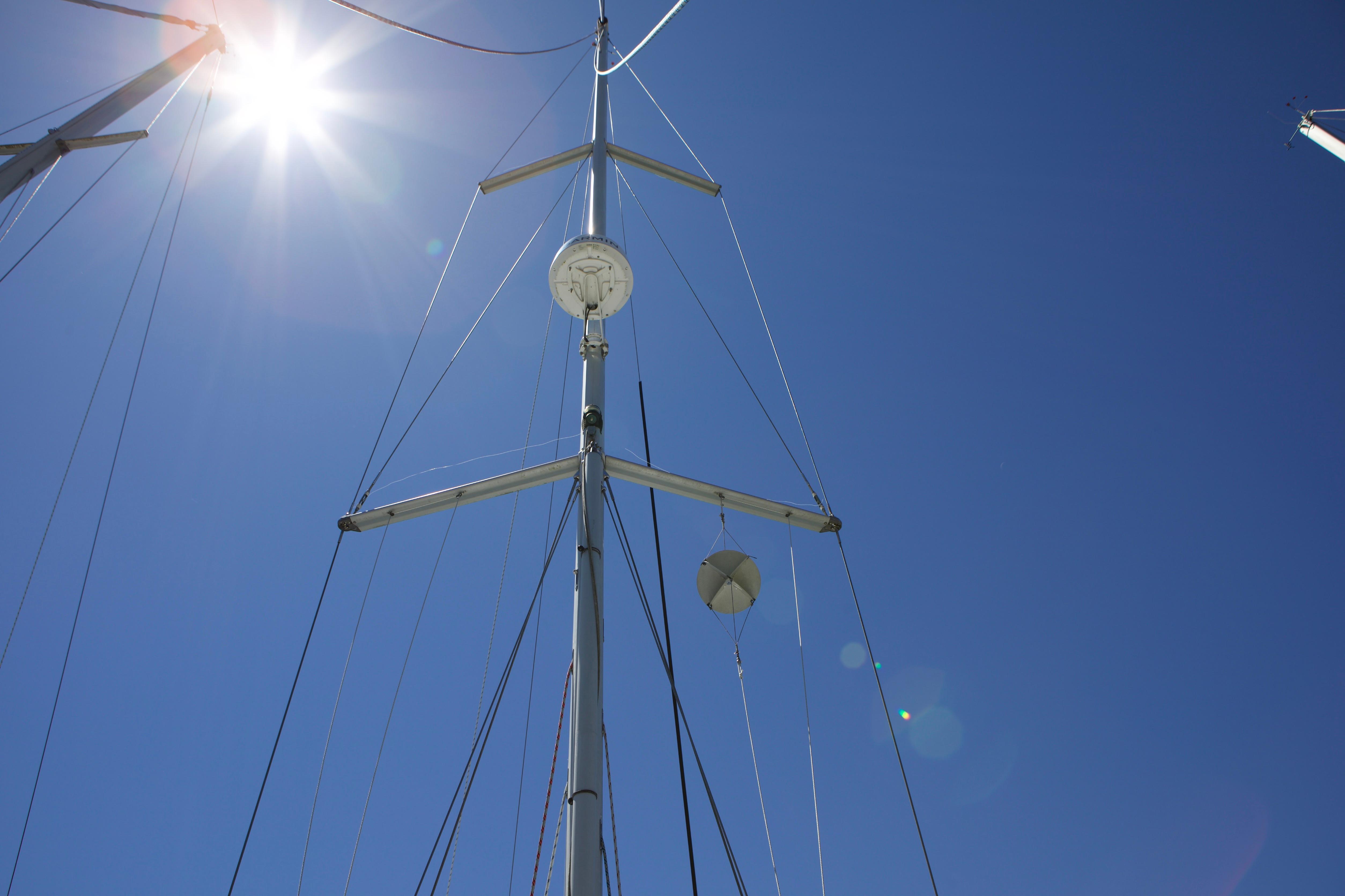 Mast of 2005 Beneteau 423 sailboat against clear blue sky with sun flare.