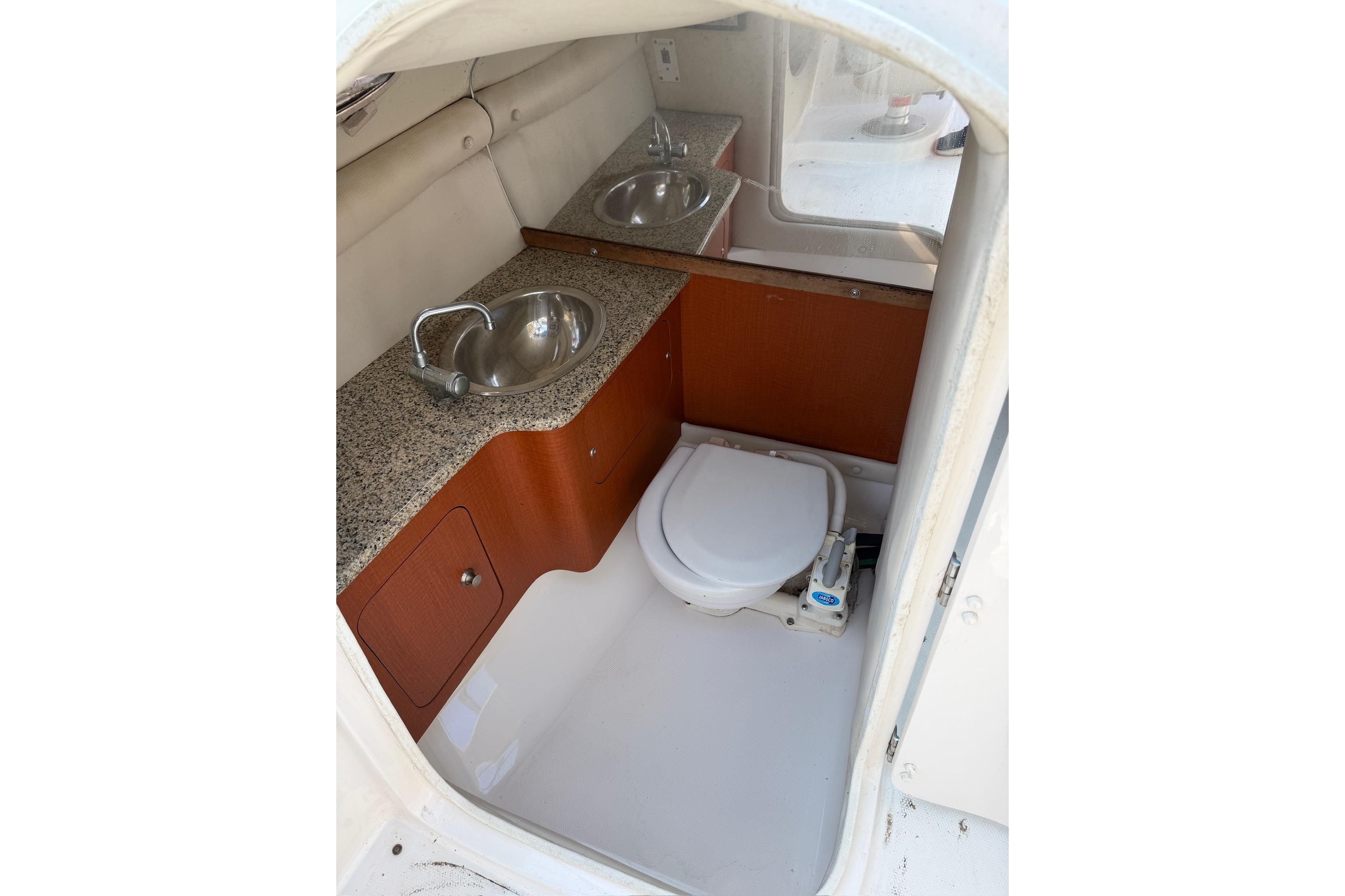 2005 Chaparral 256 SSi boat interior with sink and toilet in compact bathroom.
