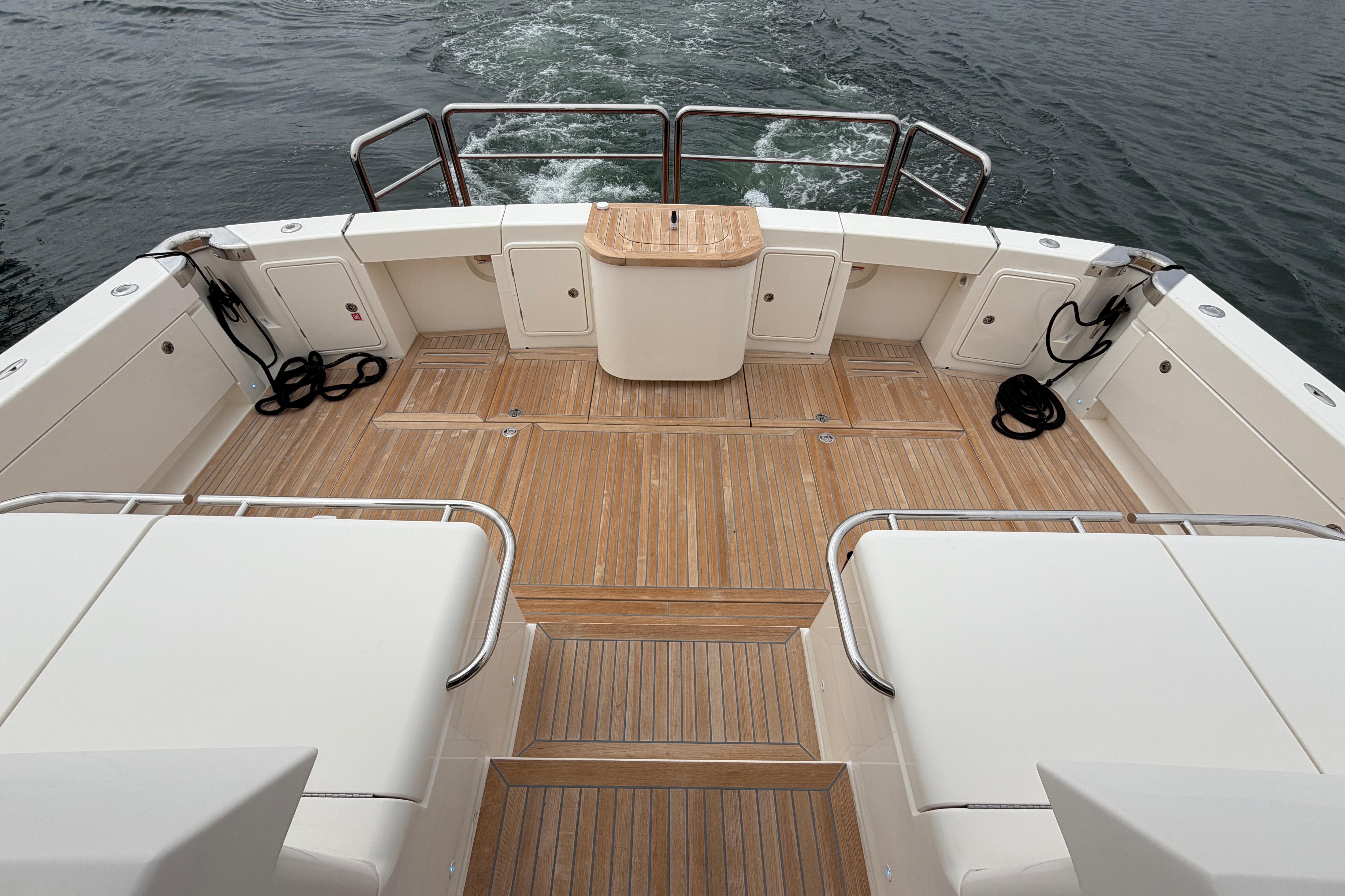 2023 Riviera 645 SUV yacht deck with teak flooring and seating, cruising on water.